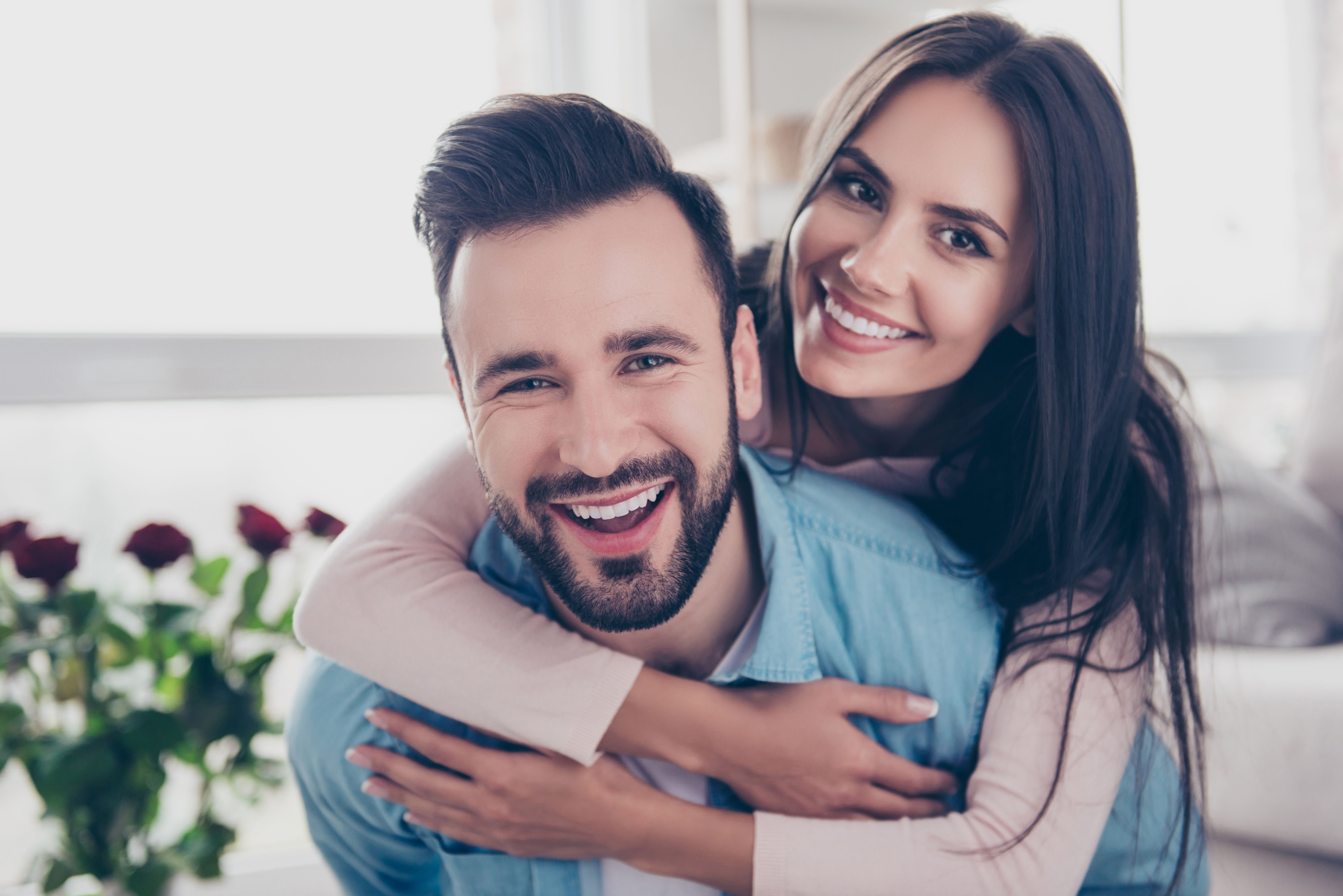 A woman hugs her partner from behind. | Source: Shutterstock