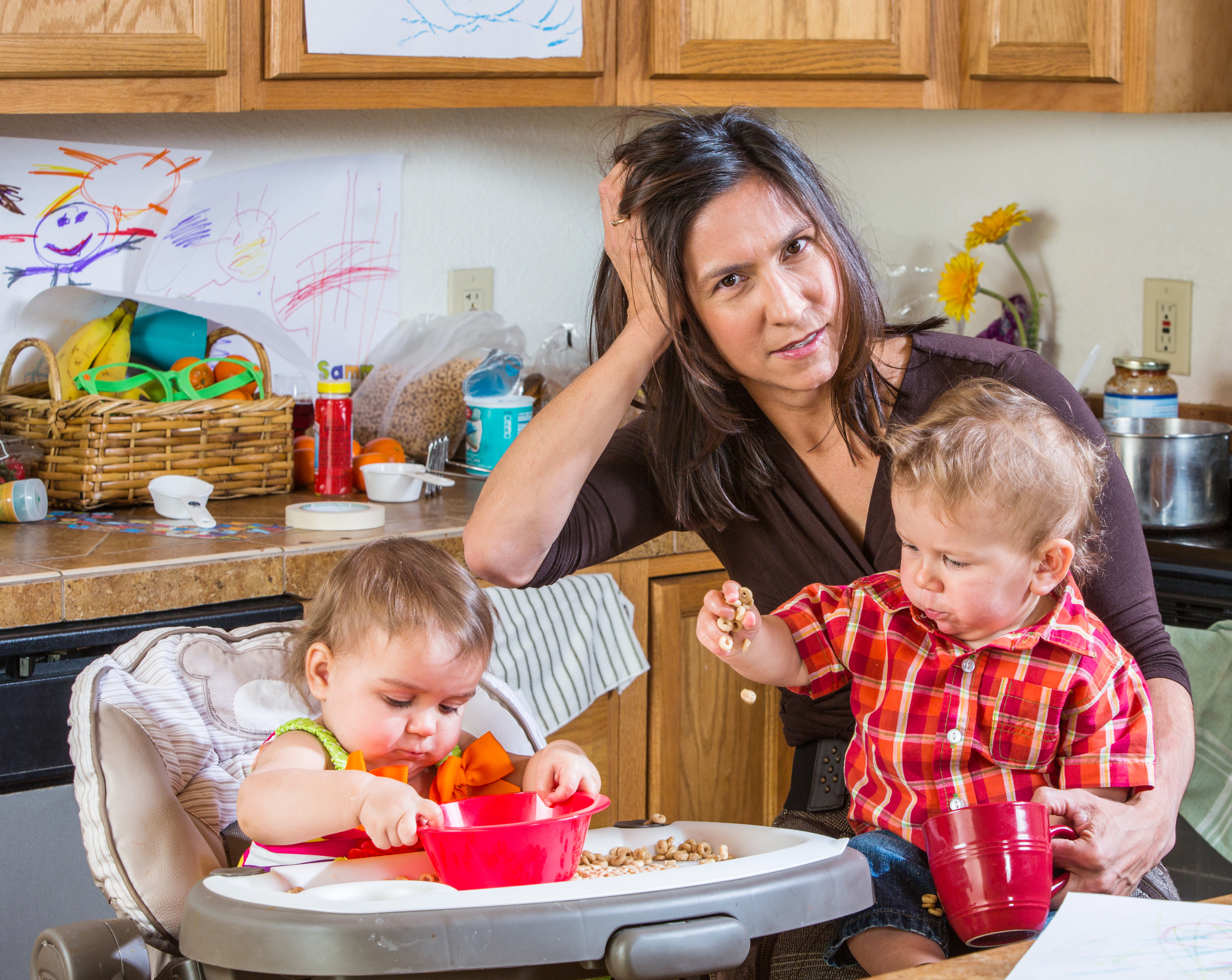 A stressed-out mother in the kitchen with her babies | Source: Shutterstock