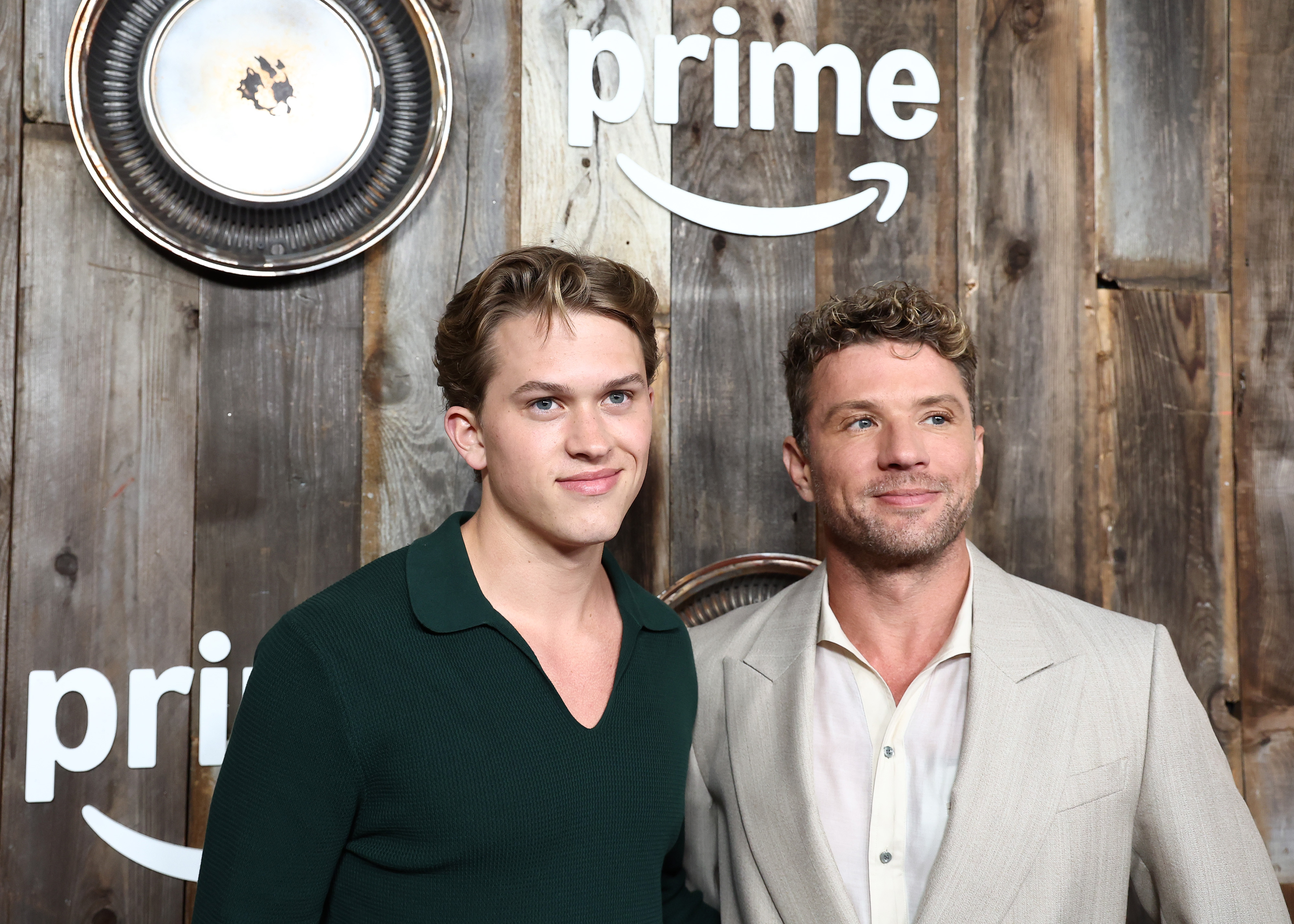 Deacon and Ryan Phillippe pose at the "Motorheads" premiere at the Academy Museum's Ted Mann Theater, smiling warmly in front of the branded backdrop. Ryan wears a light-toned suit, while Deacon keeps it sleek in a deep green knit top and dark slacks.