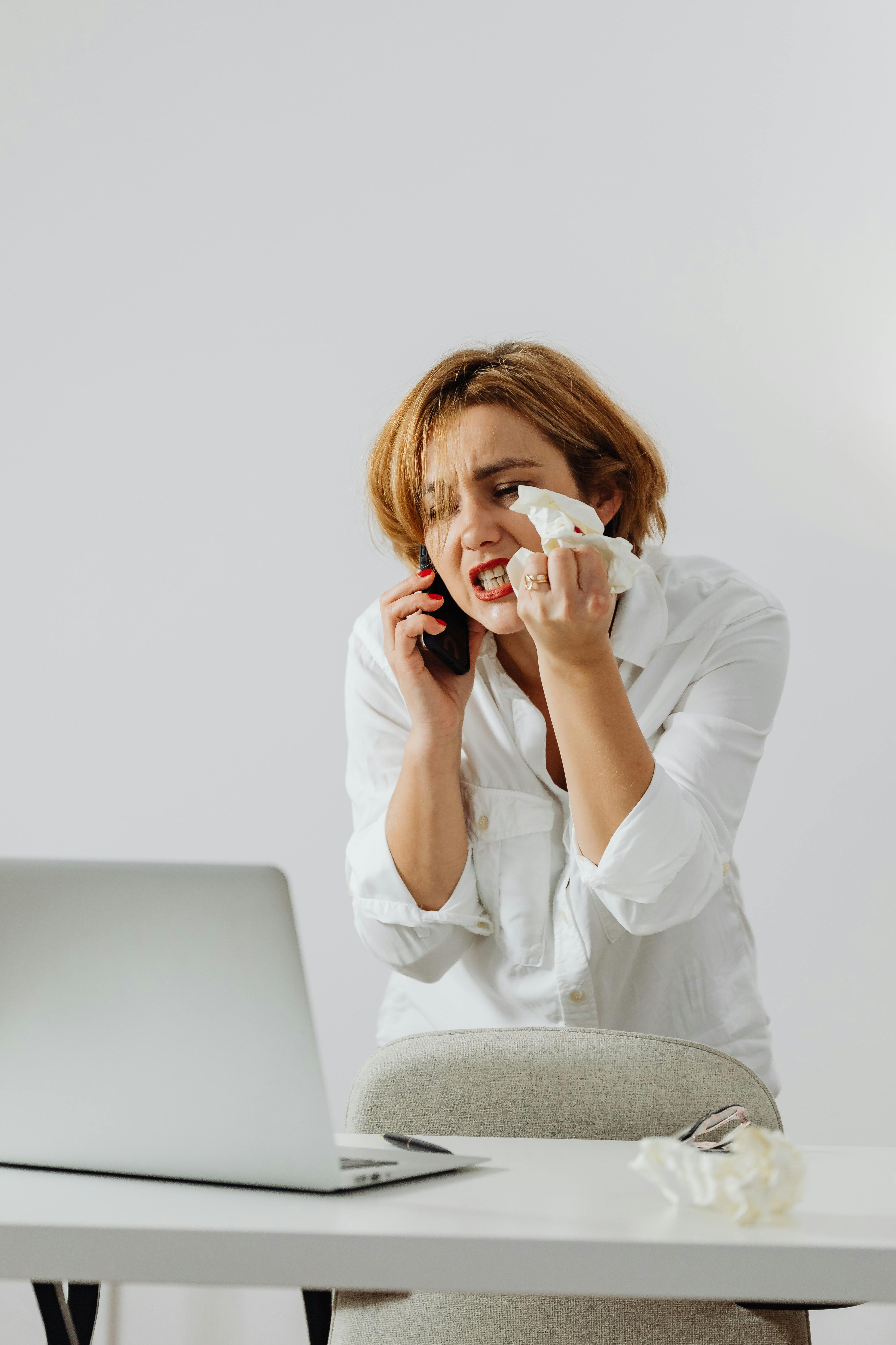 An upset woman crumpling a tissue while on the phone | Source: Pexels