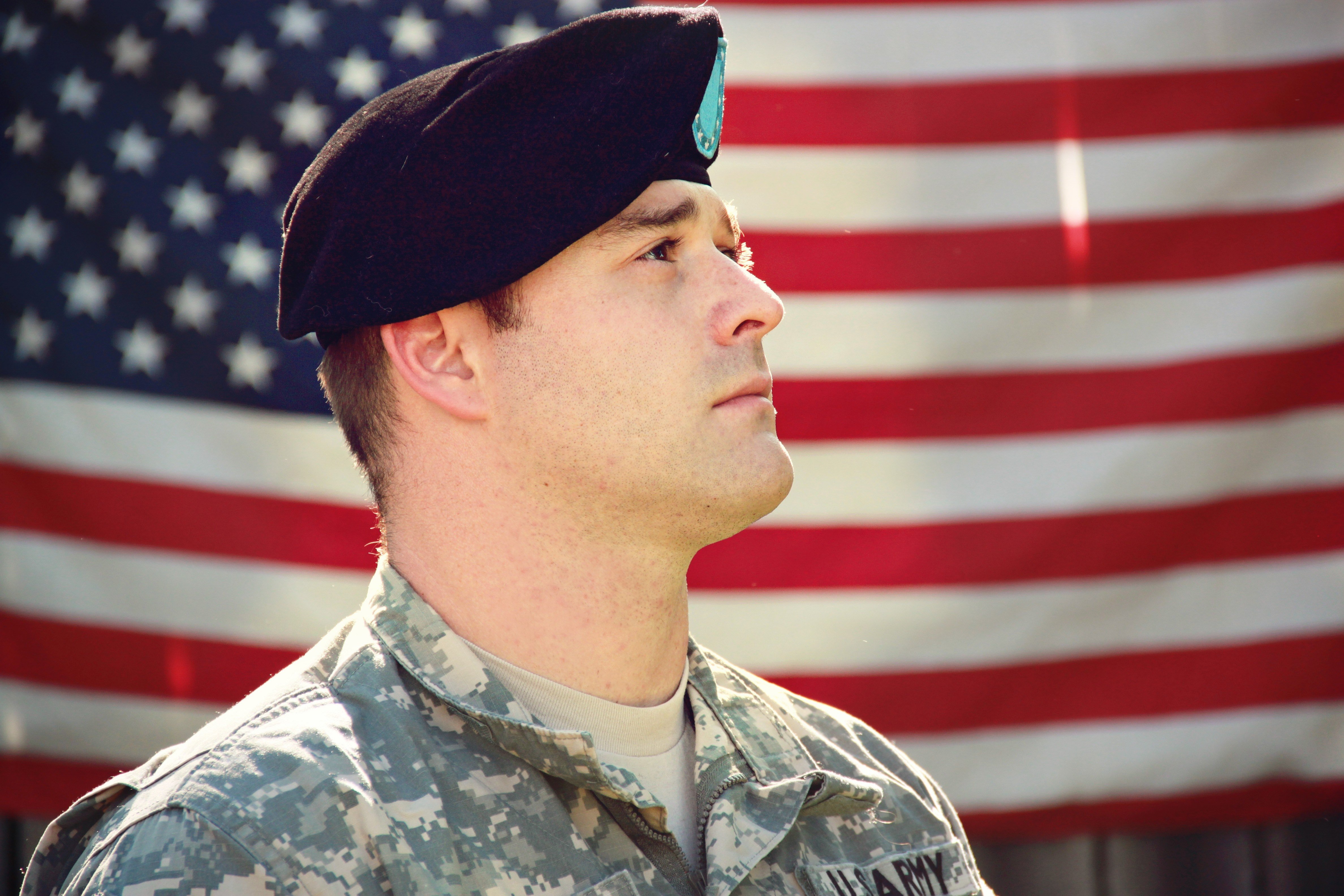 Soldado posando de perfil con la bandera de los Estados Unidos de América en el fondo. | Foto: Pexels