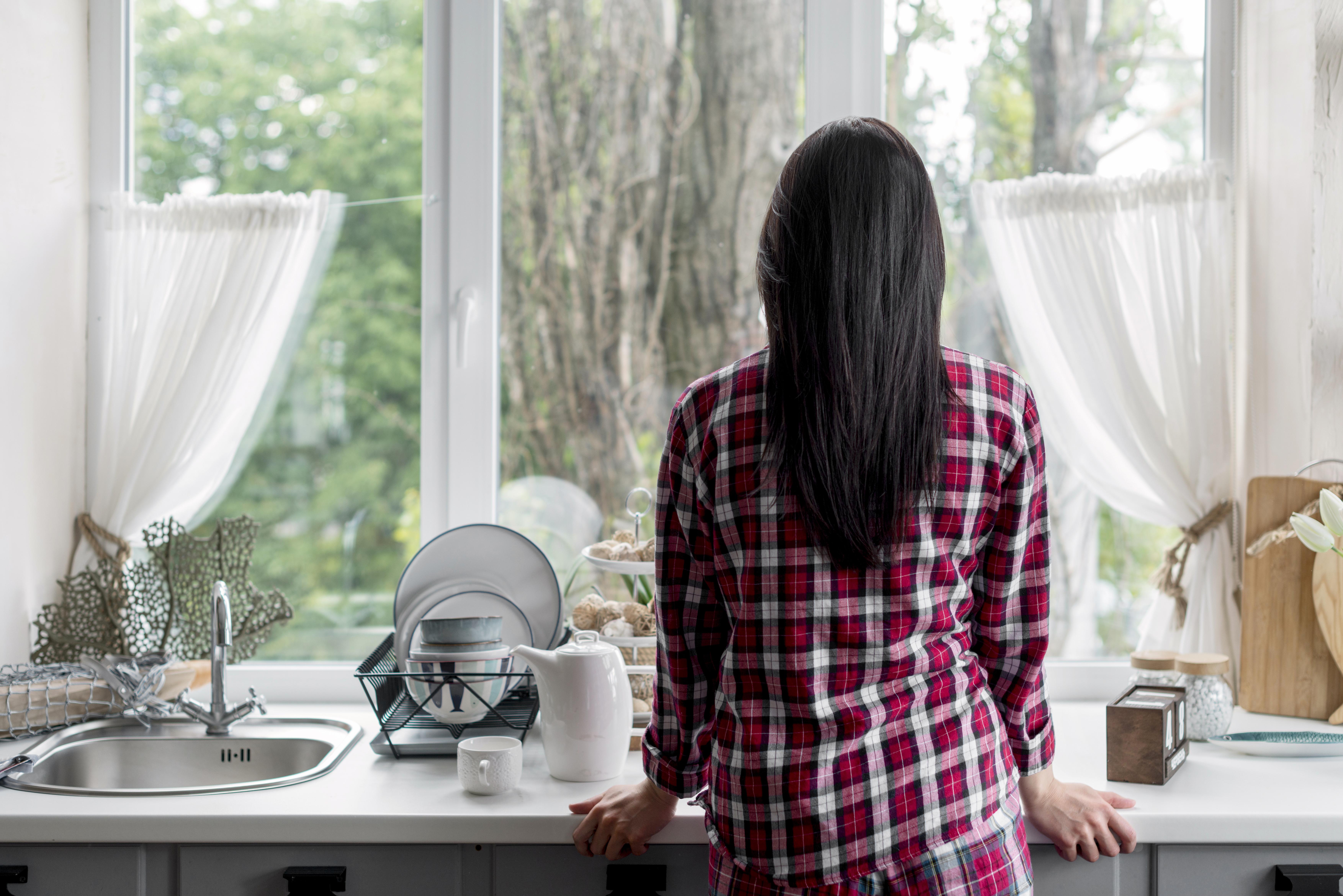 Rear view of a woman looking out the kitchen window | Source: Freepik