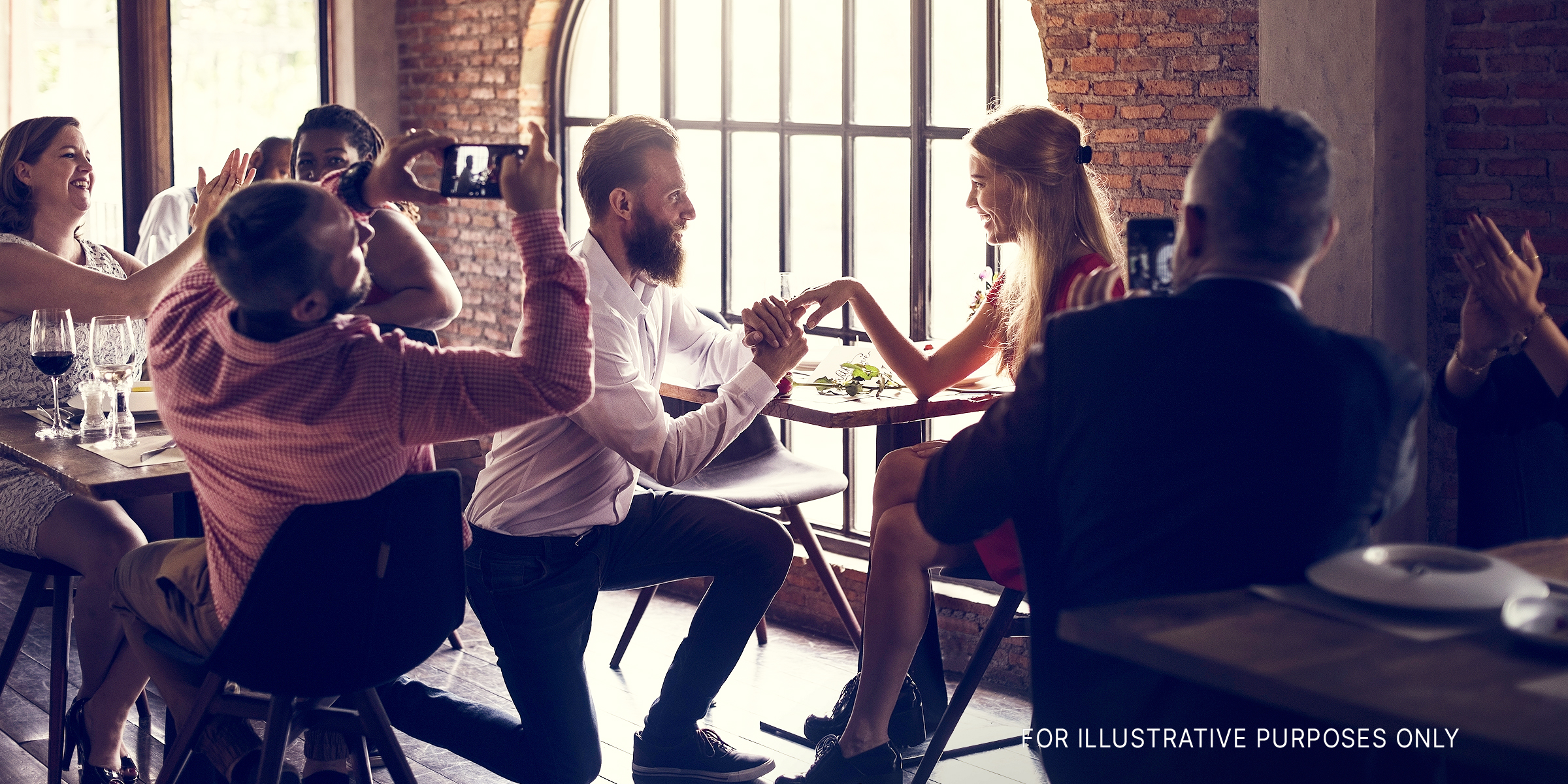Man on his knee, proposing at a restaurant. | Source: Shutterstock