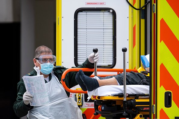 An NHS worker wearing a mask and goggles takes a man with an unknown condition from an ambulance at the St Thomas' Hospital on March 31, 2020 in London, England. | Photo: Getty Images