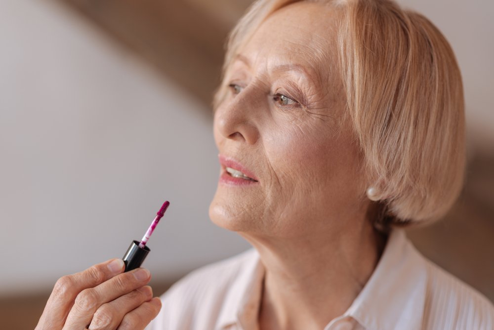 Mujer mayor aplicandose brillo de labios. I Foto: Shutterstock