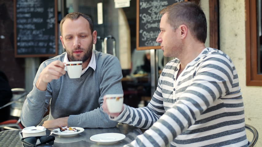 Two male friends drinking coffee at a coffee shop | Source: Shutterstock