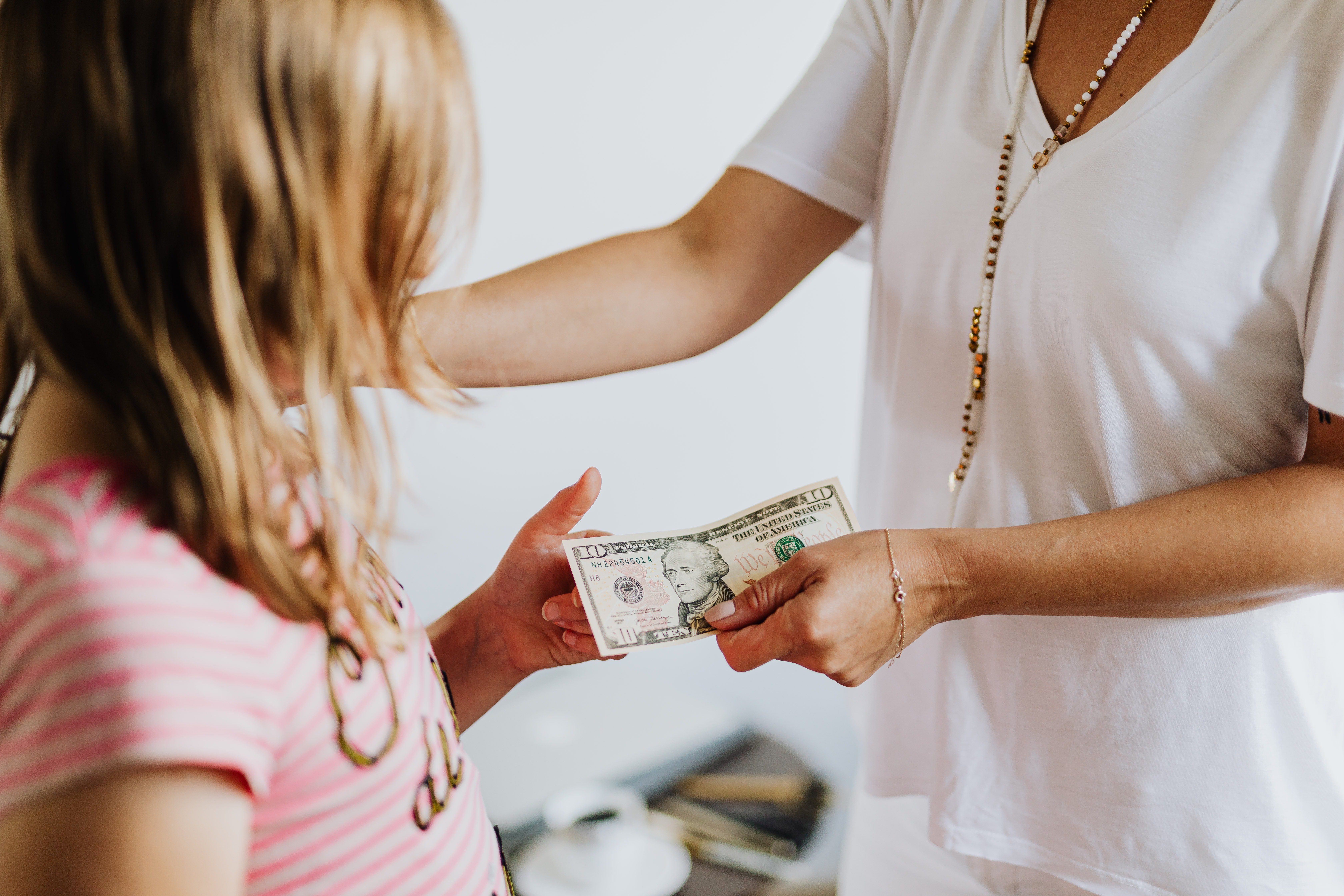 Una mujer dándole dinero a una niña. | Foto: Pexels