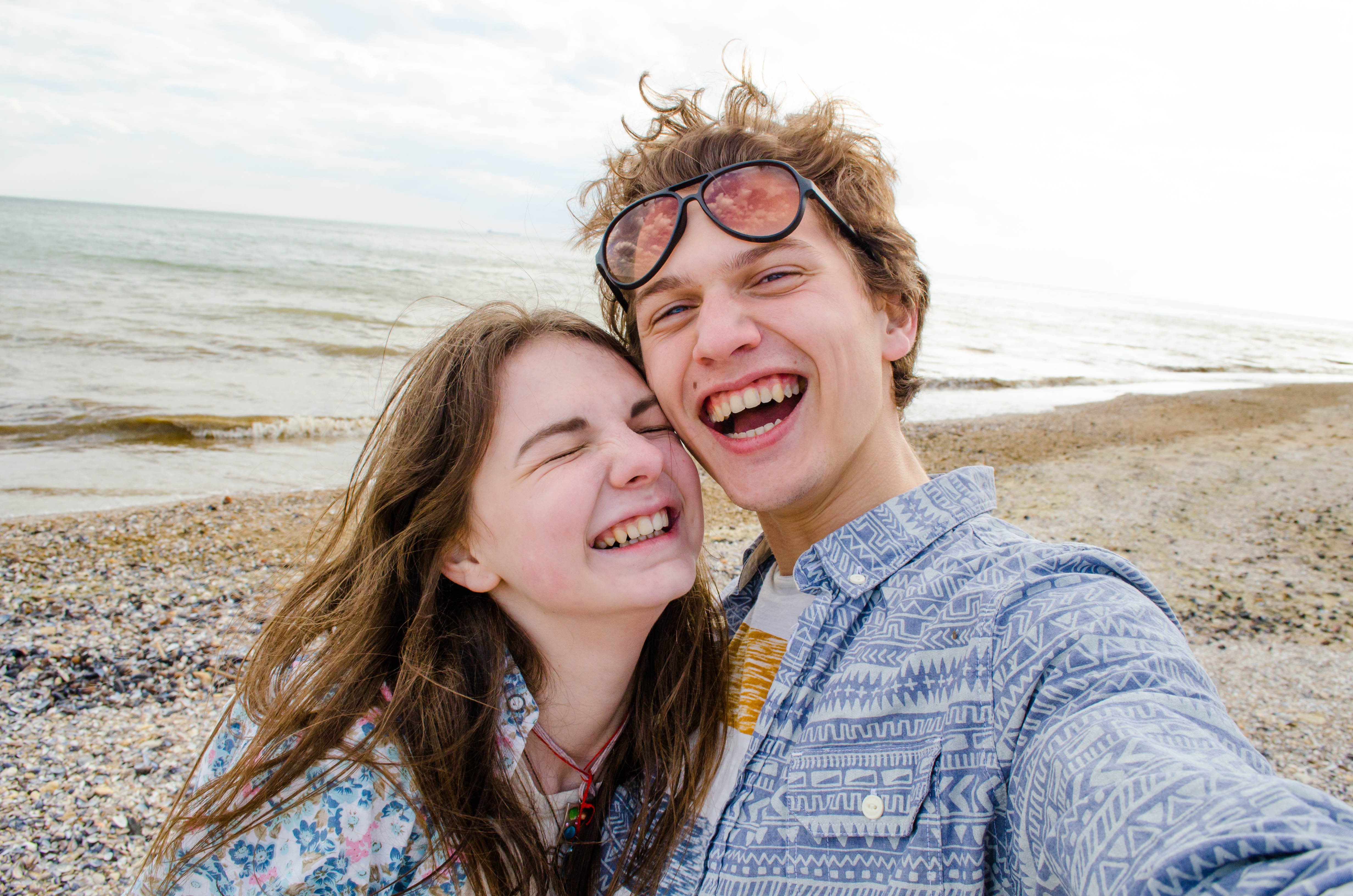 A young couple taking a selfie on the beach | Source: Shutterstock
