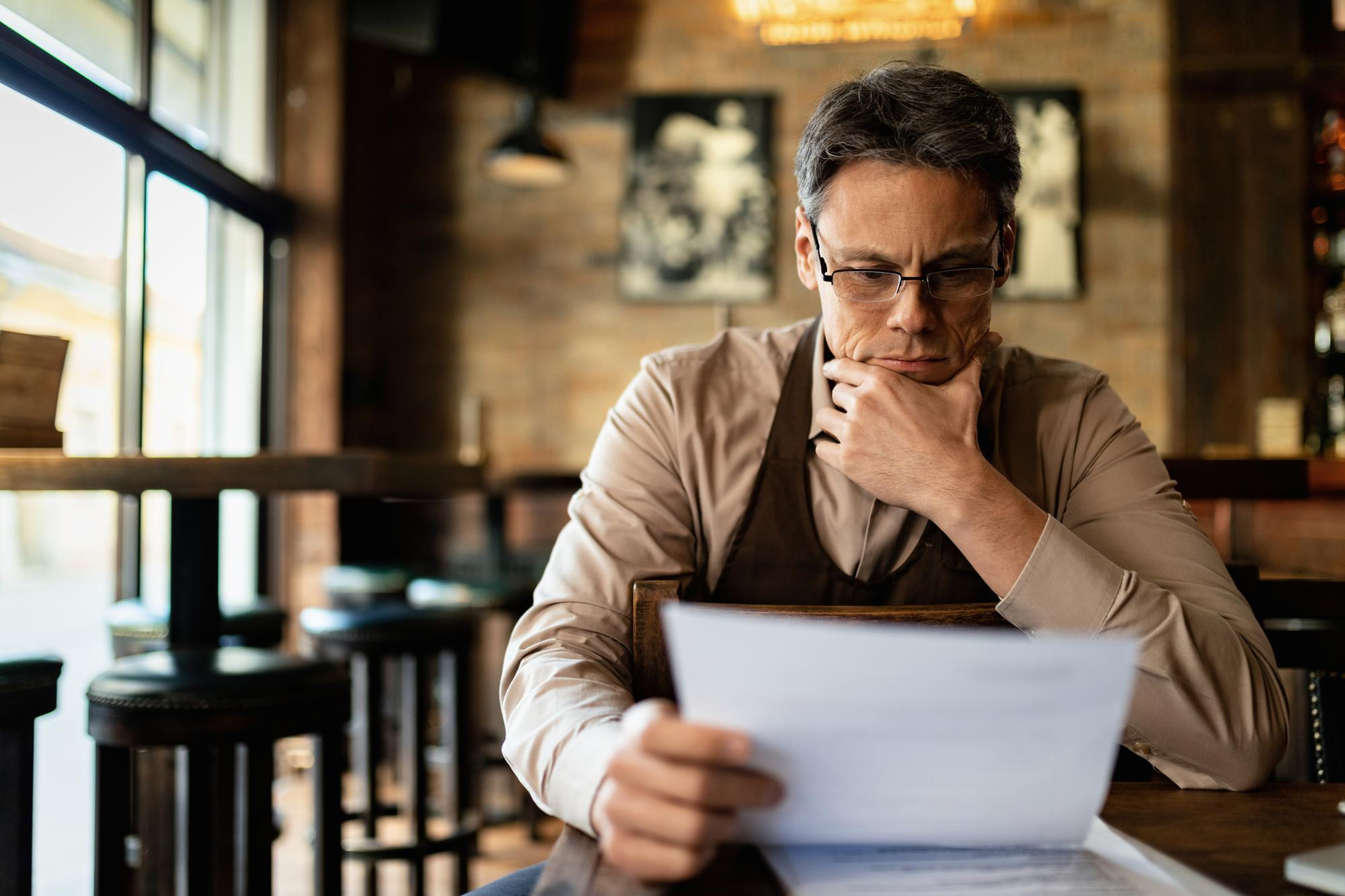 A man looking contemplative while reading something on a piece of paper | Source: Freepik