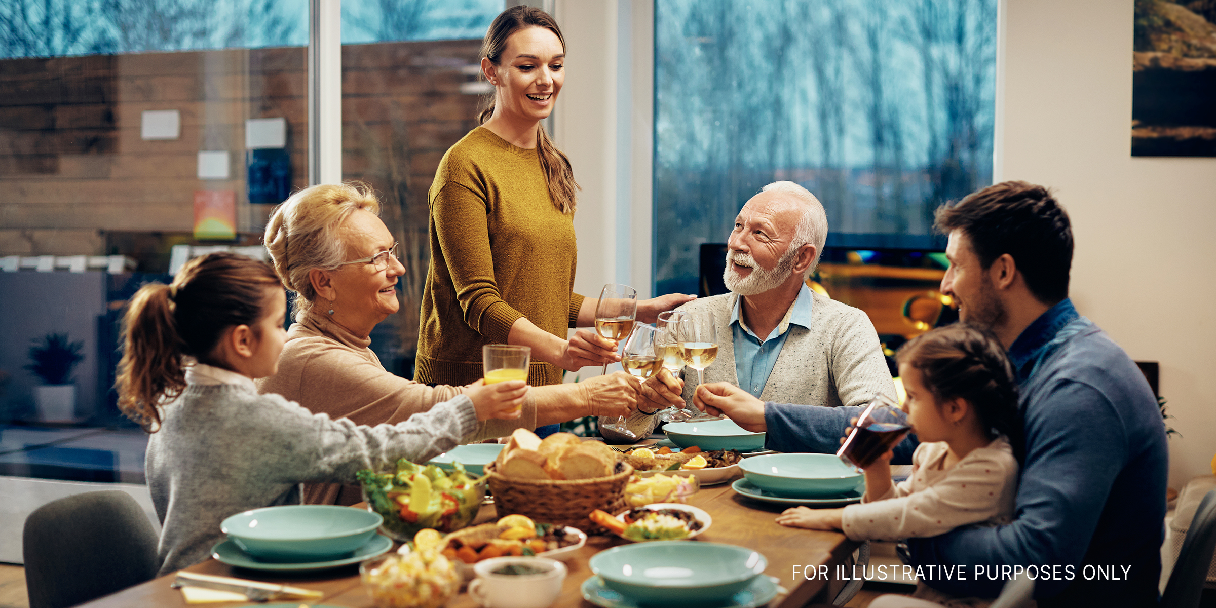 A happy extended family toasting while having lunch together in the dining room | Source: Shutterstock