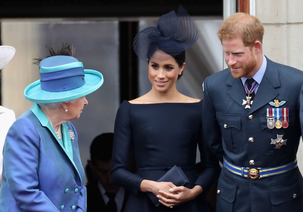 Queen Elizabeth II, Meghan Markle, and Prince Harry watch the RAF flypast on the balcony of Buckingham Palace on July 10, 2018, in London, England. | Source: Getty Images.