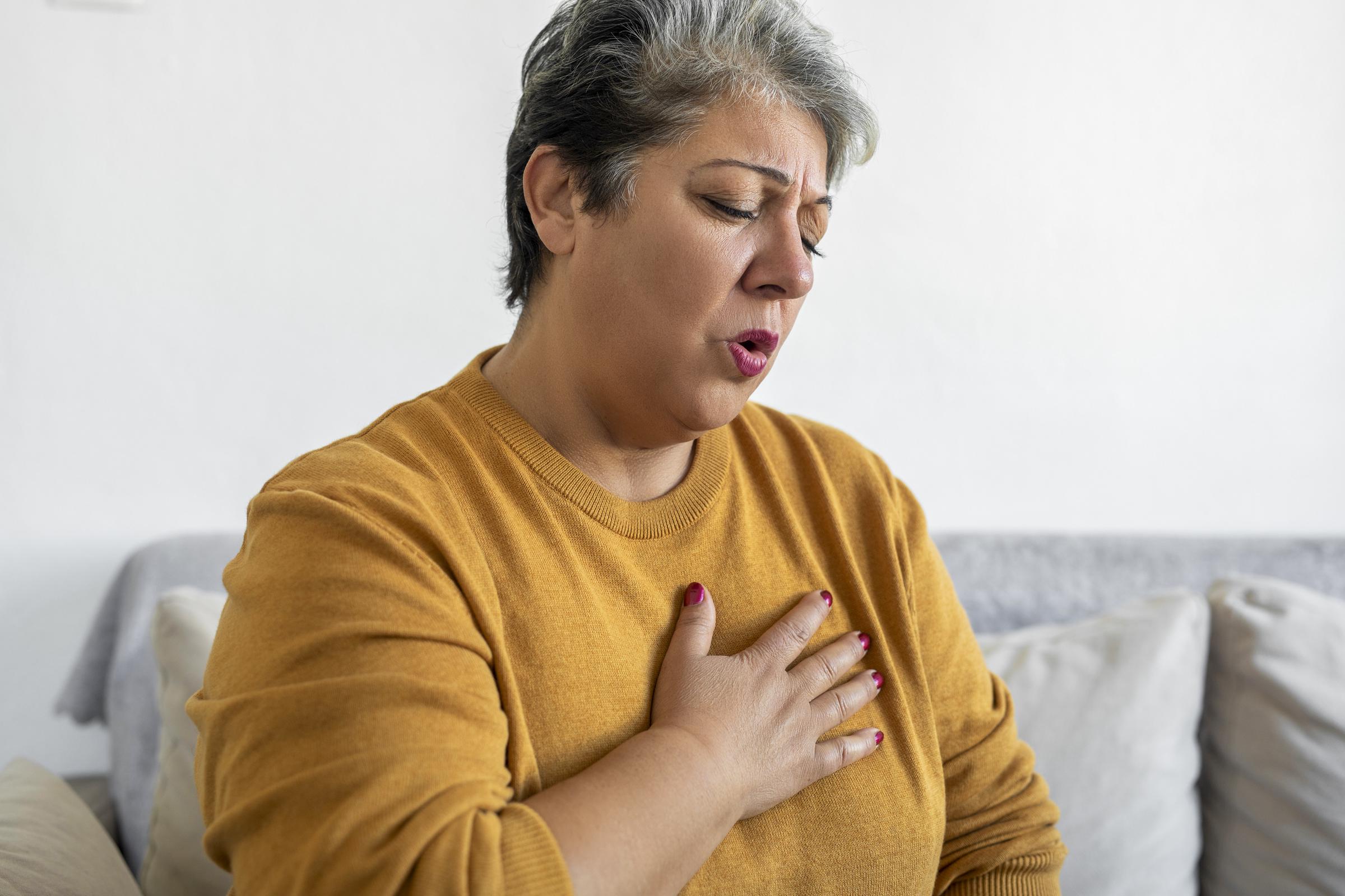 Woman clutching her chest, experiencing pain and difficulty breathing | Source: Getty Images