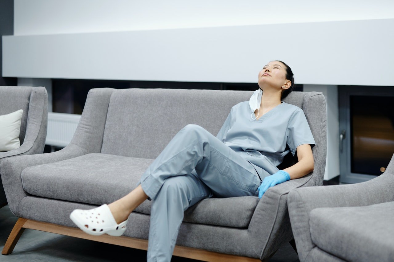 Photo of a tired nurse sitting on a couch | Photo: Pexels