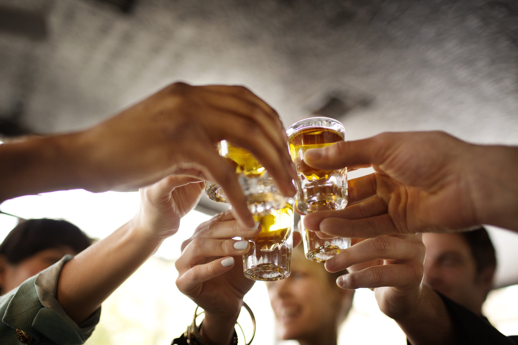 Freunde stoßen mit einem Schuss Tequila in einer Bar an. | Quelle: Getty Images