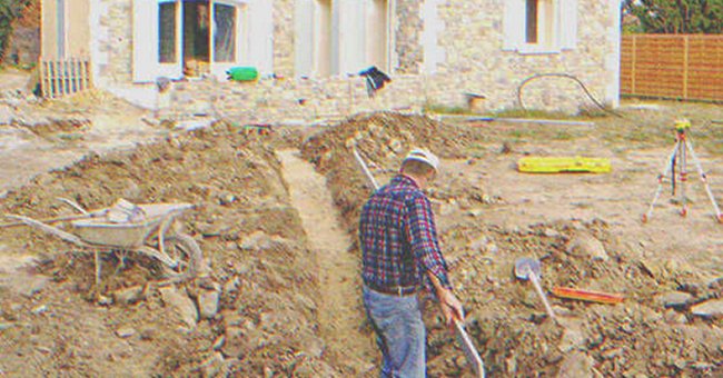 A man digging on the ground next to a house | Source: Shutterstock