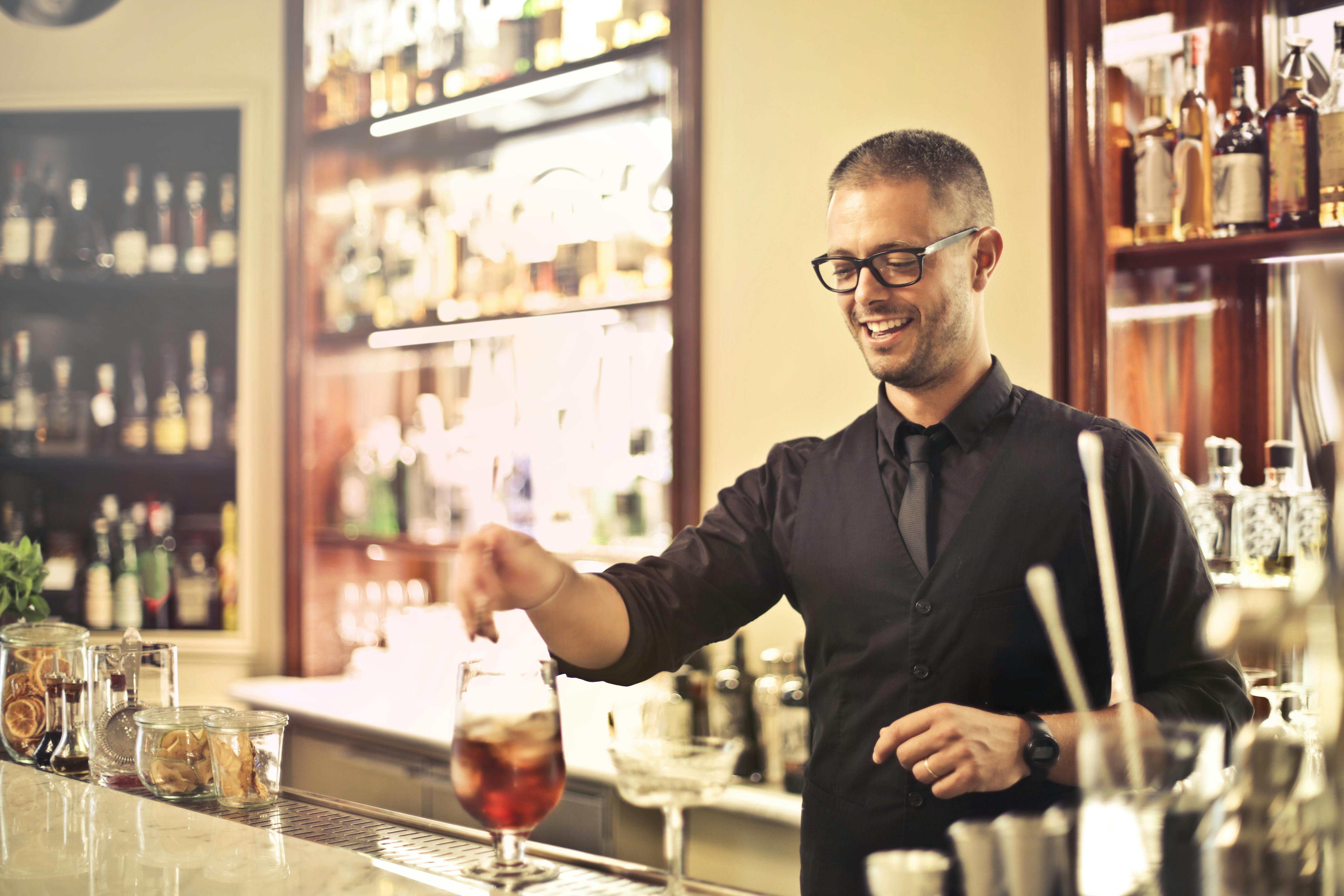 A smiling waiter preparing a drink | Source: Pexels