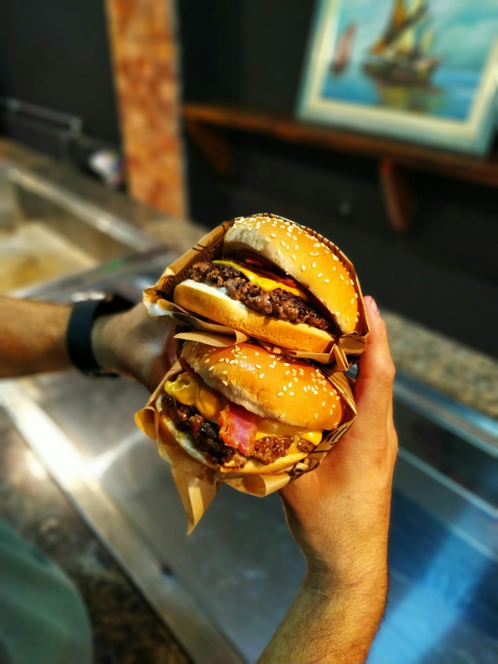 Close-up of a man holding two burgers | Source: Pexels