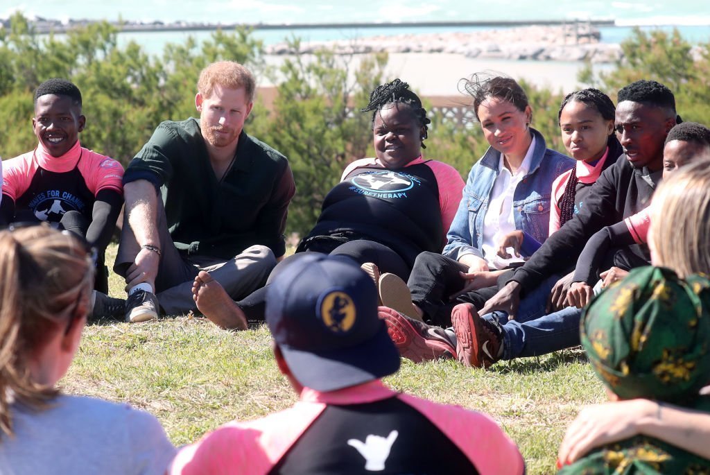 Prince Harry and Meghan Markle join surf mentors and participate in a group activity as they visit Waves for Change, an NGO, at Monwabisi Beach. | Source: Getty Images
