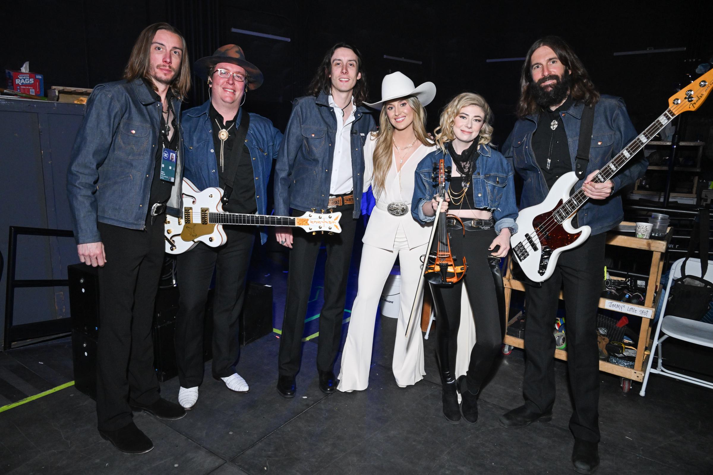 Wilson also poses with her band, who are dressed in black trousers and shirts topped with denim jackets. Their coordinated look provides a striking contrast, making her stand out even more in her all-white ensemble.