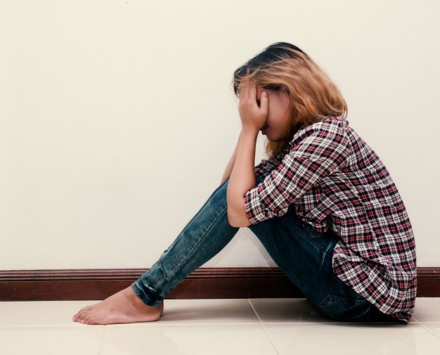 Une jeune femme qui cache son visage avec ses mains | Image: Freepik