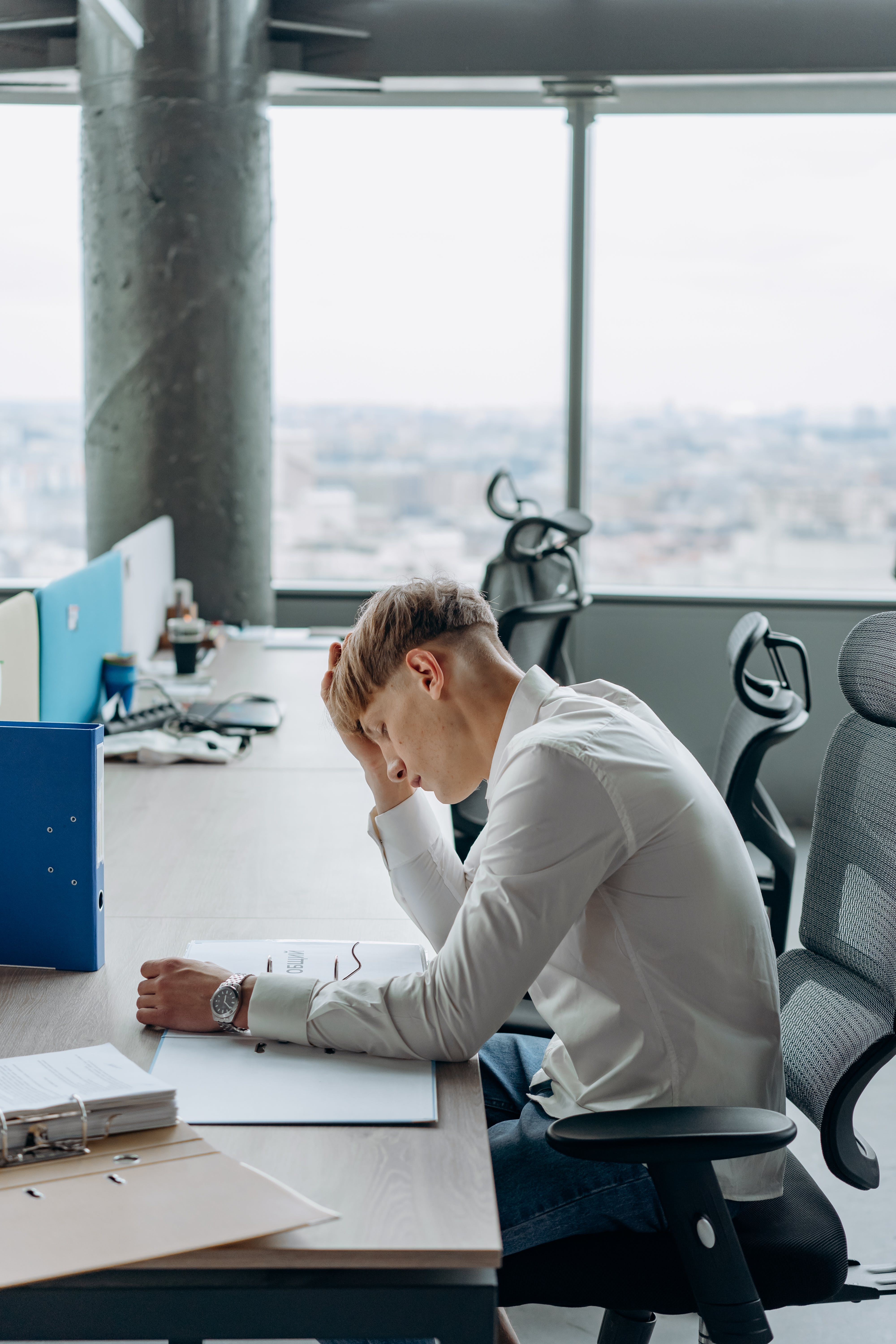 A man sitting with his hand on his head at the office | Source: Pexels