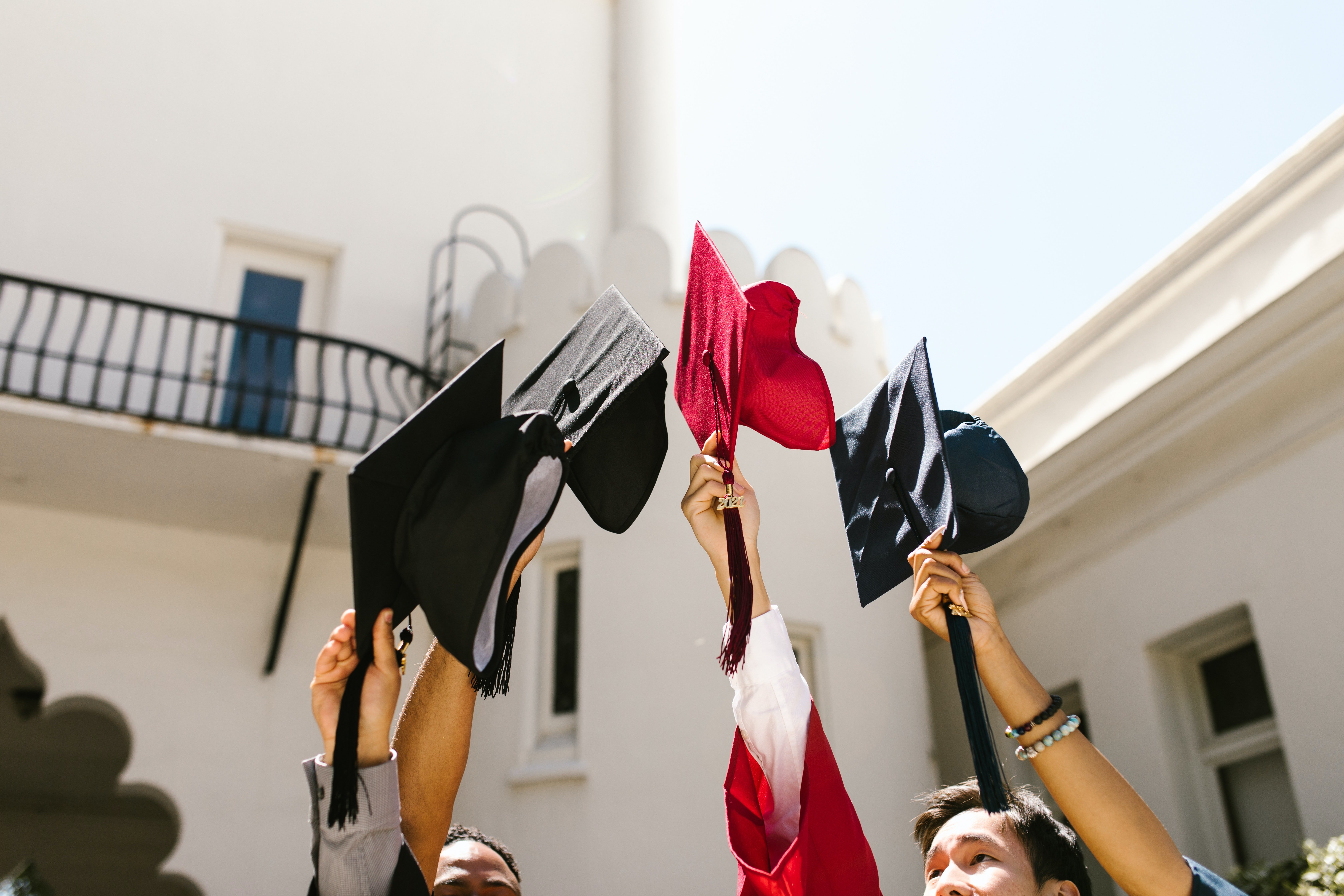 Graduating students holding up their caps. | Photo: Pexels