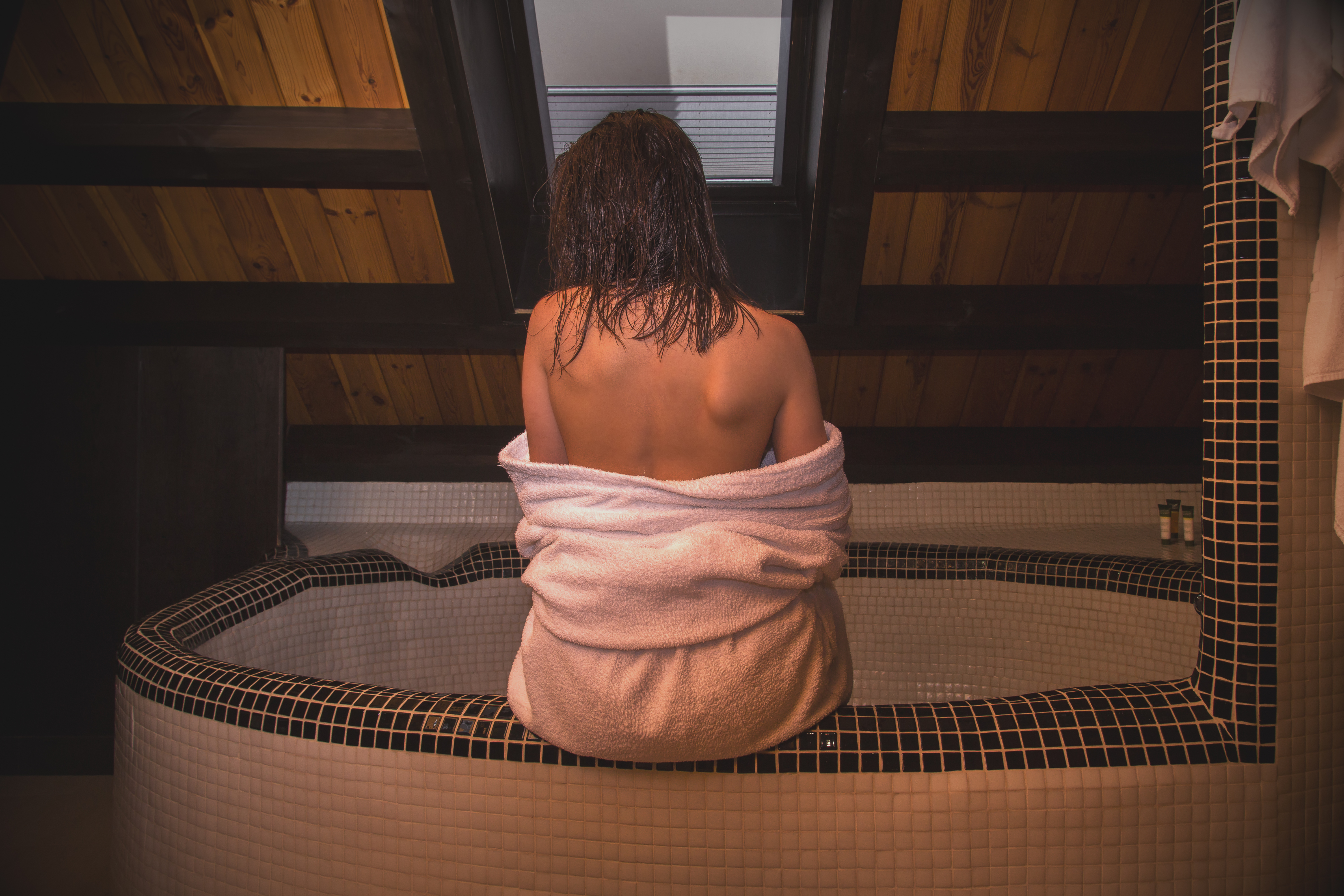 Girl with a bare back is sitting in the bathroom. | Source: Shutterstock