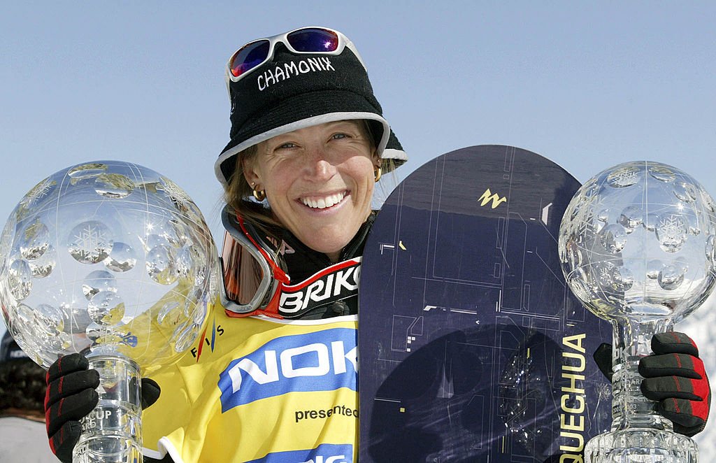 Karine Ruby de France célèbre avec ses trophées pour avoir remporté le slalom géant parallèle et la Coupe du monde de snowboard le 16 mars 2003 à Arosa, en Suisse. | Photo : Getty Images