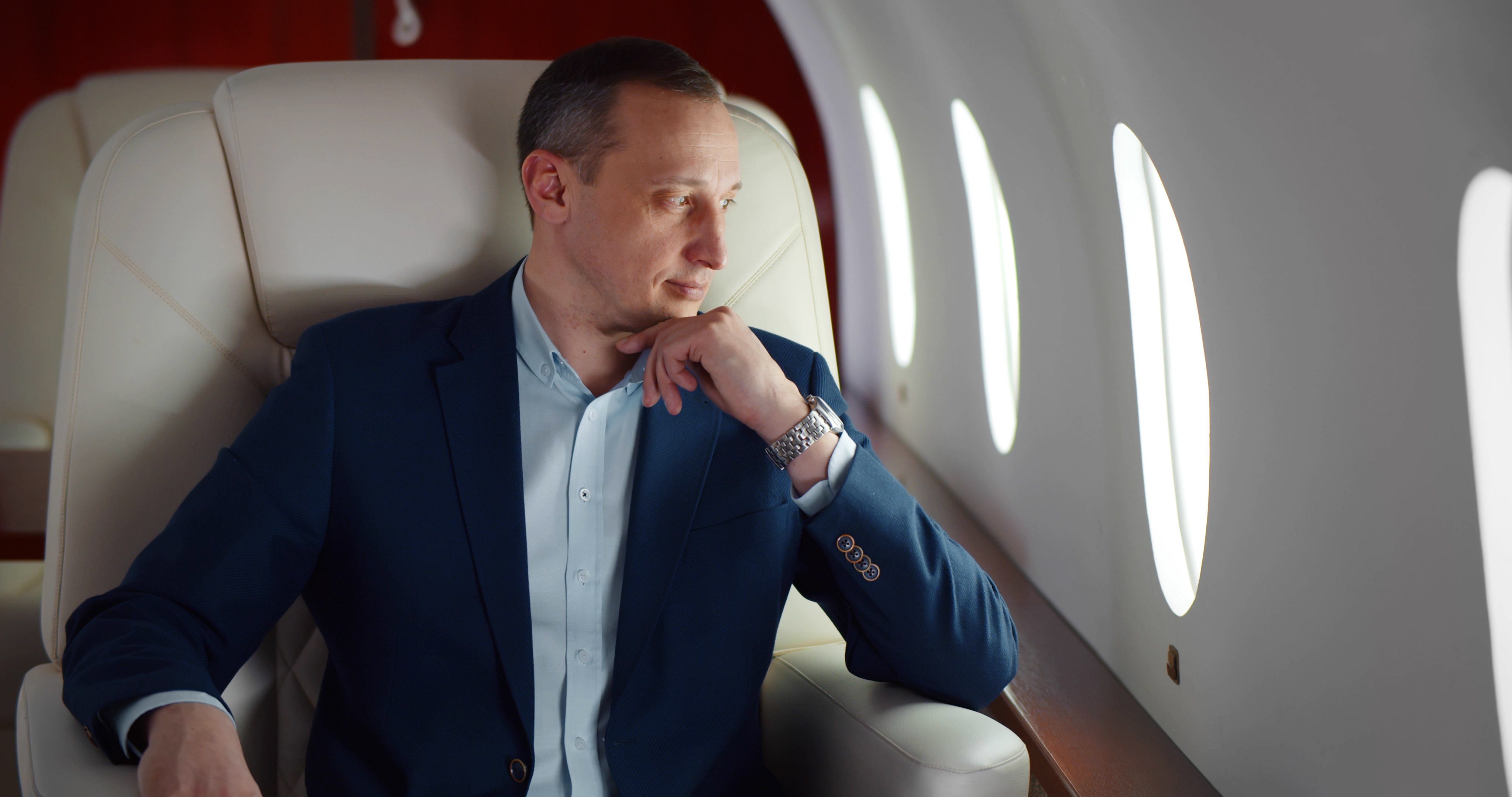 A businessman in a suit is pictured on a first-class flight | Source: Shutterstock