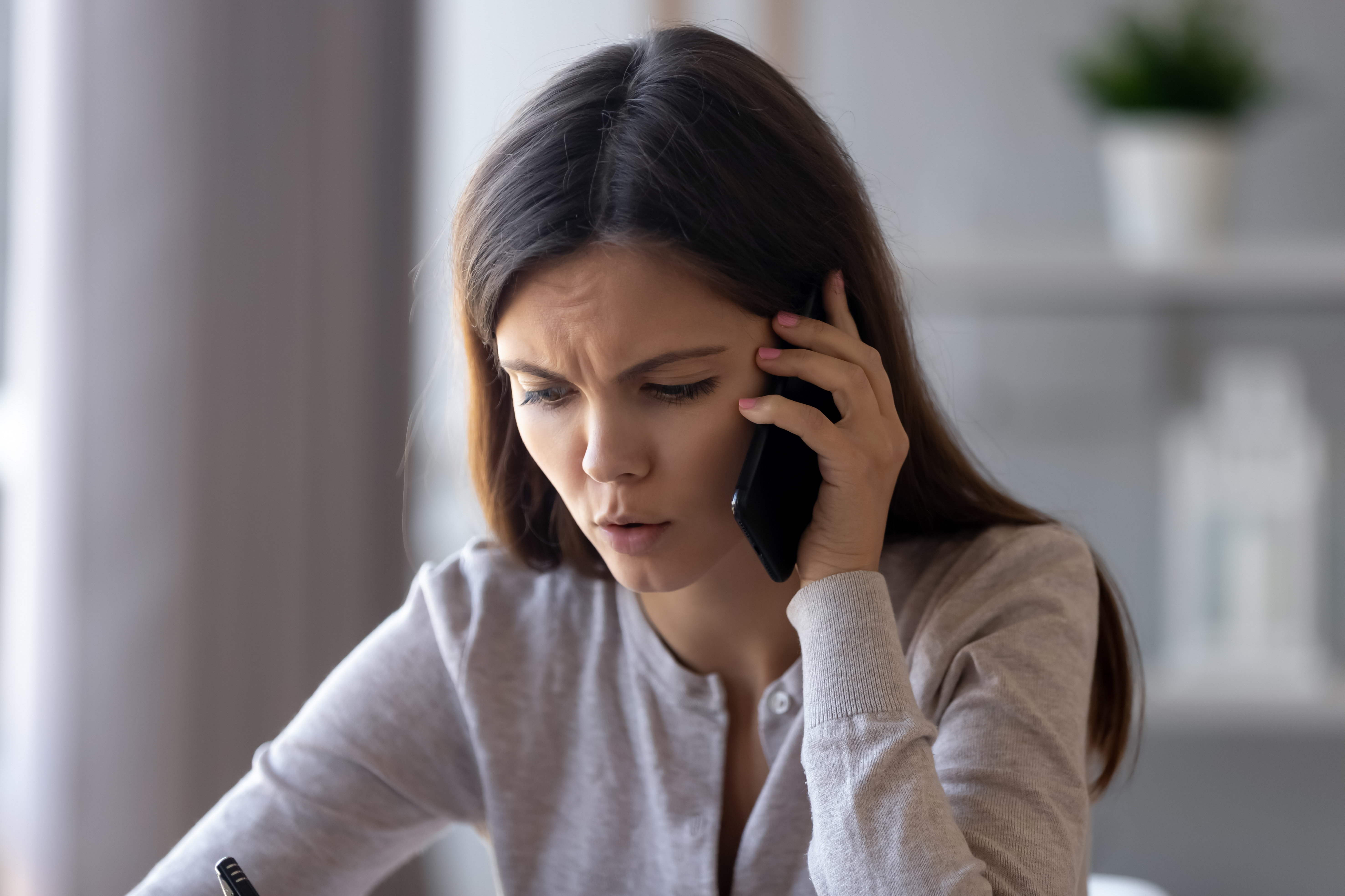 An upset young woman talking on her phone | Source: Shutterstock