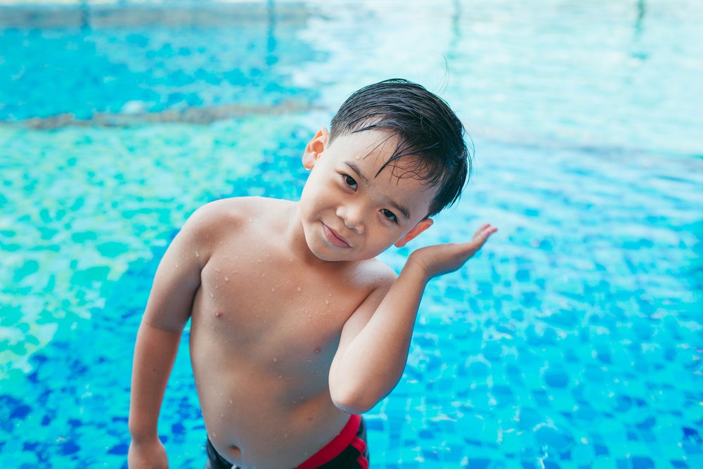 Niño dentro de una piscina moviendo su cabeza para sacar el agua de sus oídos. | Foto: Shutterstock