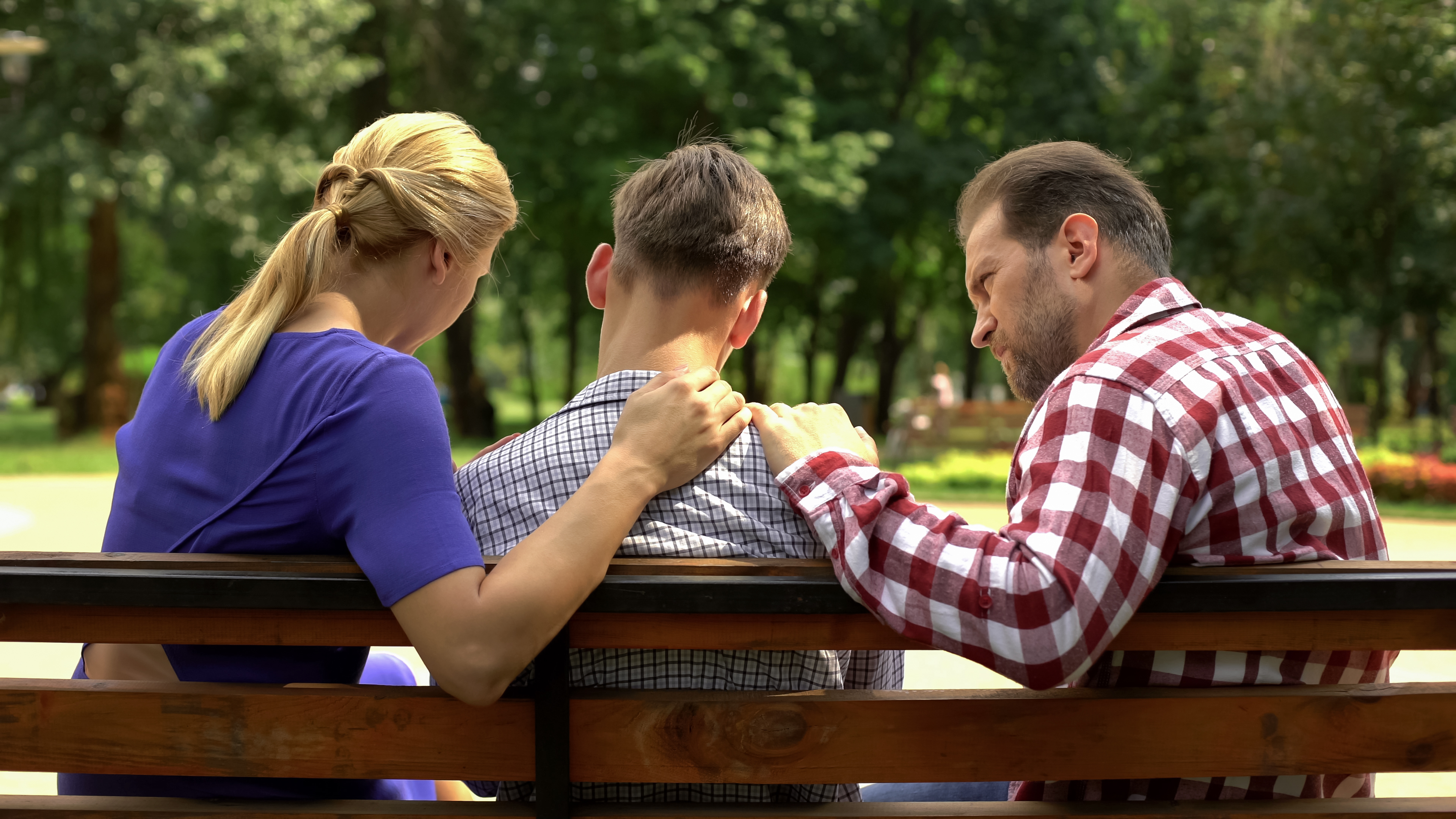 A couple is pictured talking to their teenage son in the park | Source: Shutterstock