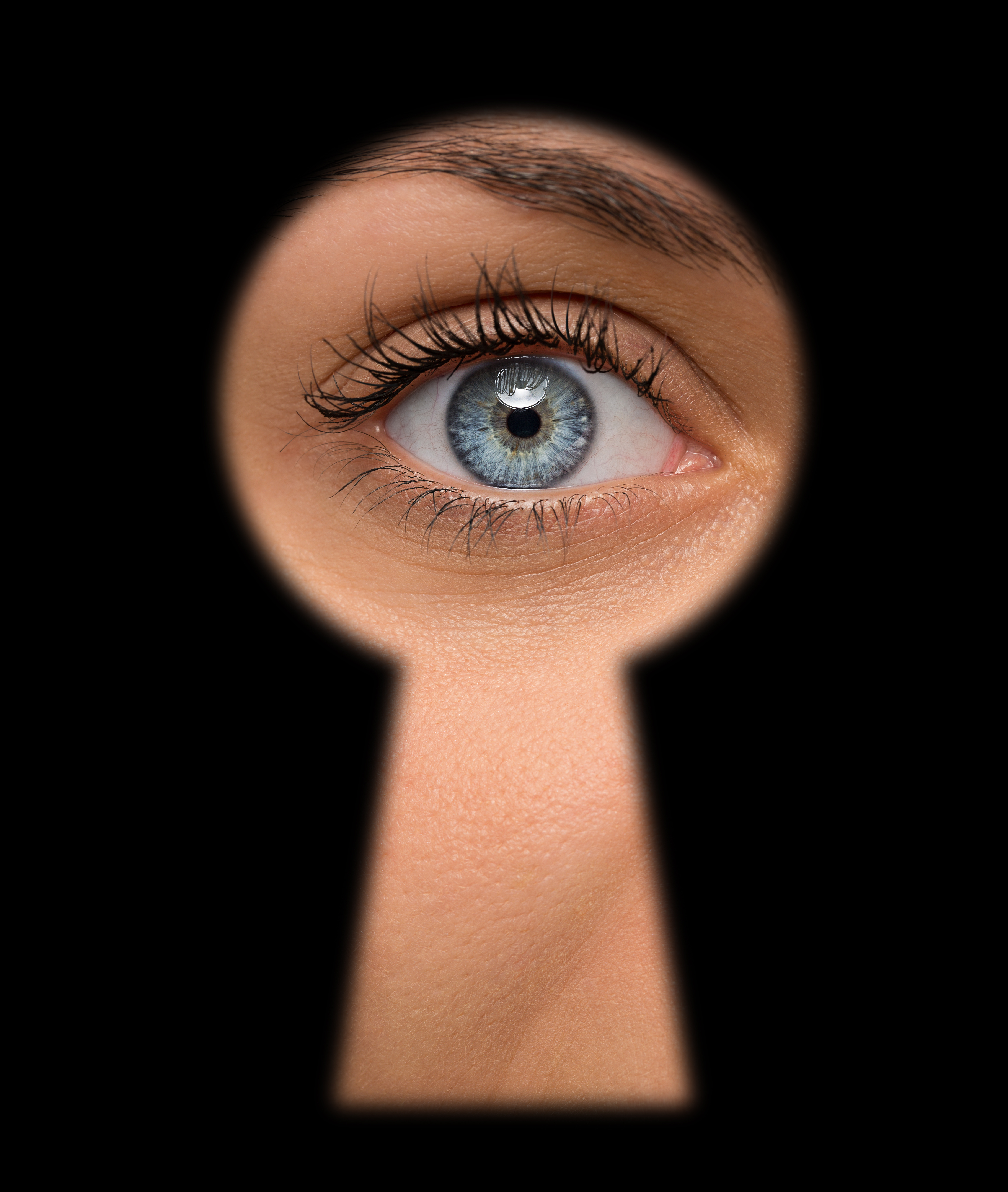 A blue-eyed woman peeps through a key hole | Source: Shutterstock