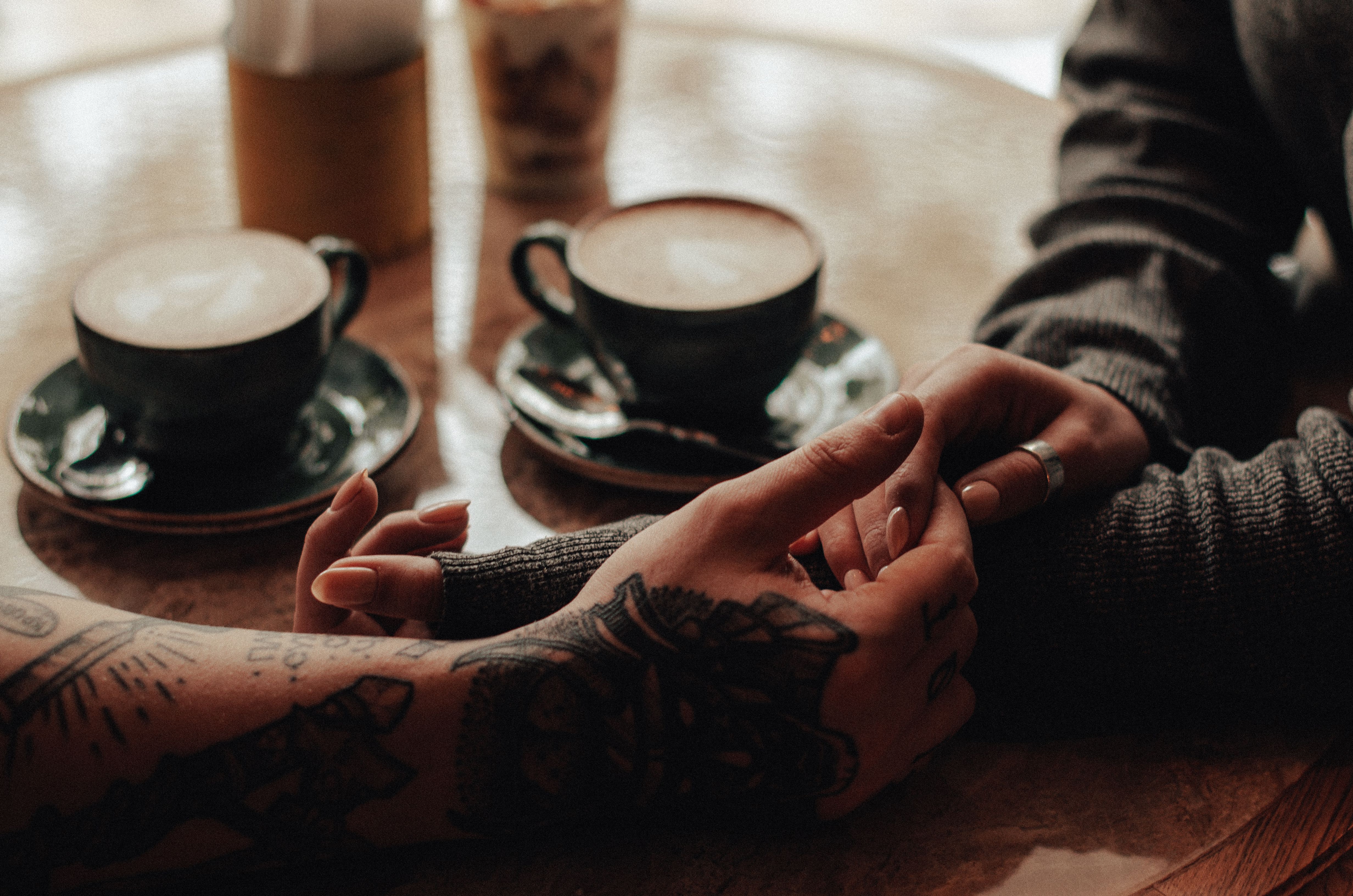 Two individuals holding hands over a table. | Source: Pexels