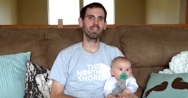 Nick Magnotti sentado en un sofá mientras sostiene a su bebé Austin de 7 meses. | Foto: YouTube.com/Alyssa Galios