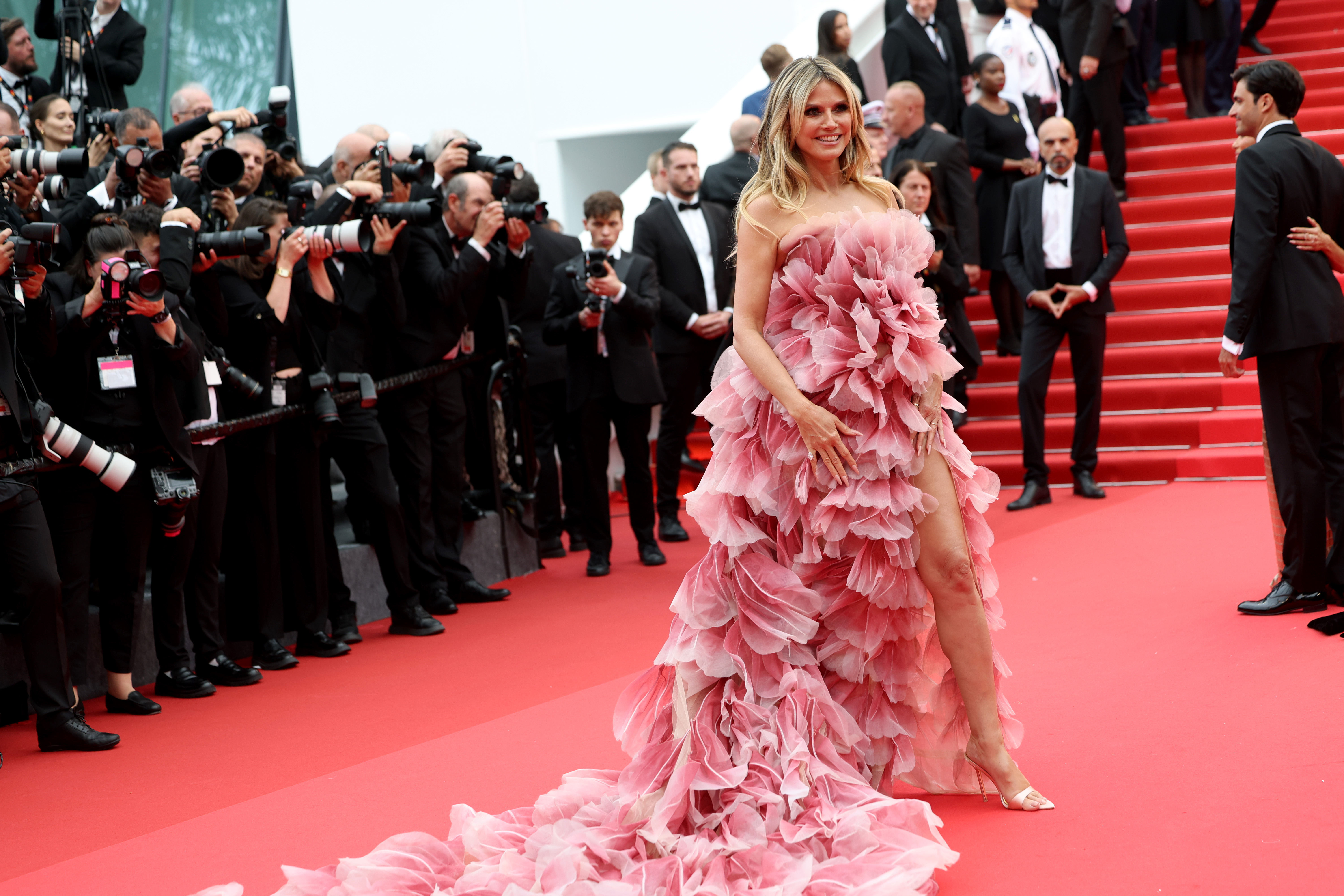 Klum smiles, clearly savoring the moment and the attention that comes with it. One leg peeks through the thigh-high slit of her gown, revealing a shimmering silver stiletto that adds to the drama of her look.
