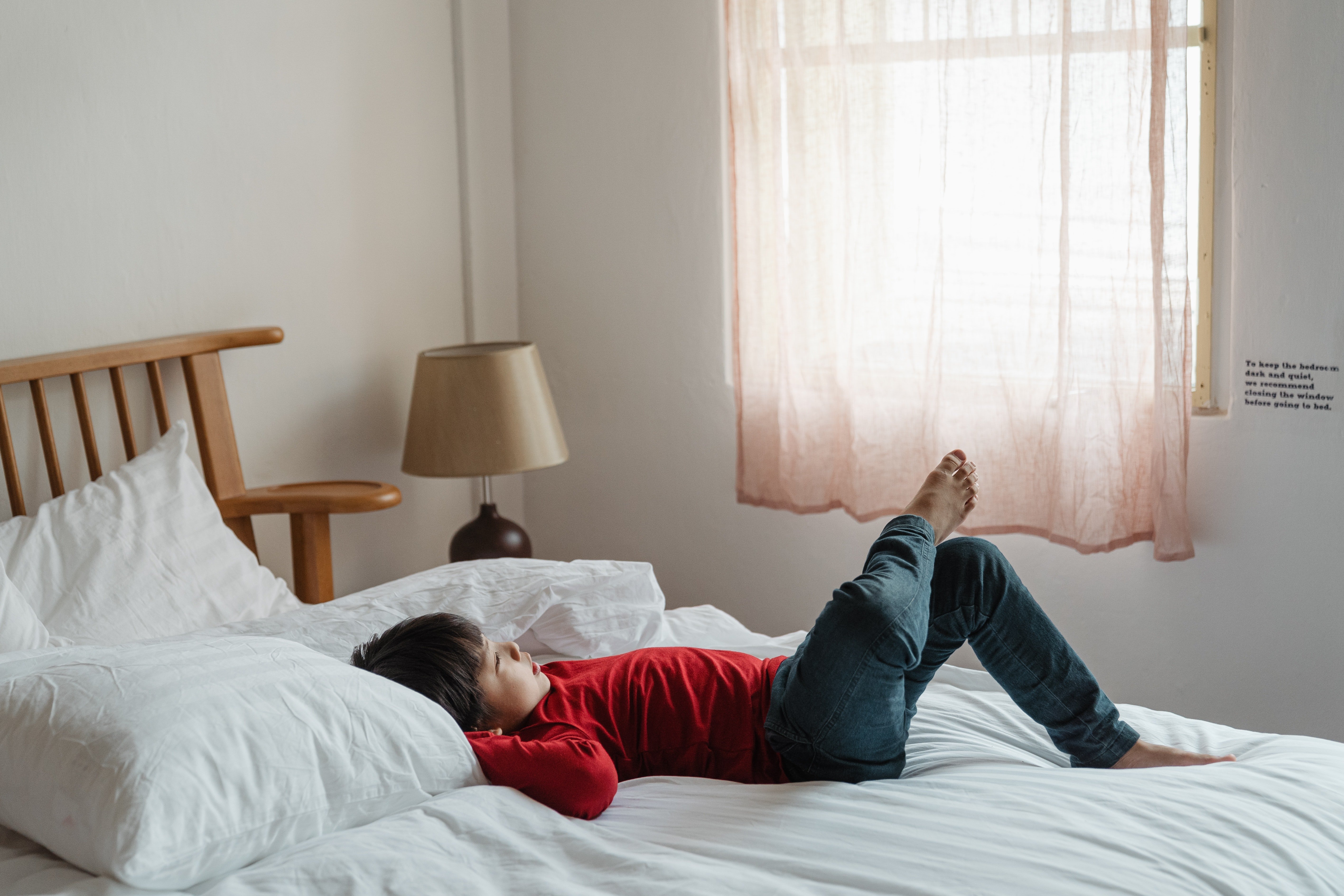 Pictured - An image of a boy lying on the bed with his leg up | Source: Pexels 