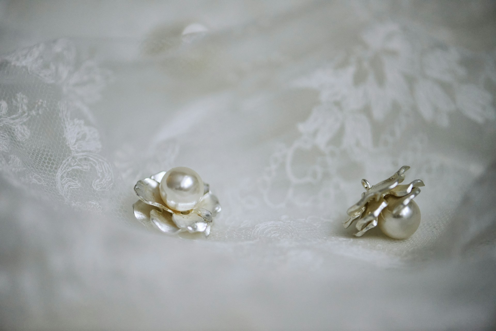 A pair of pearl earrings on a lace cloth | Source: Unsplash