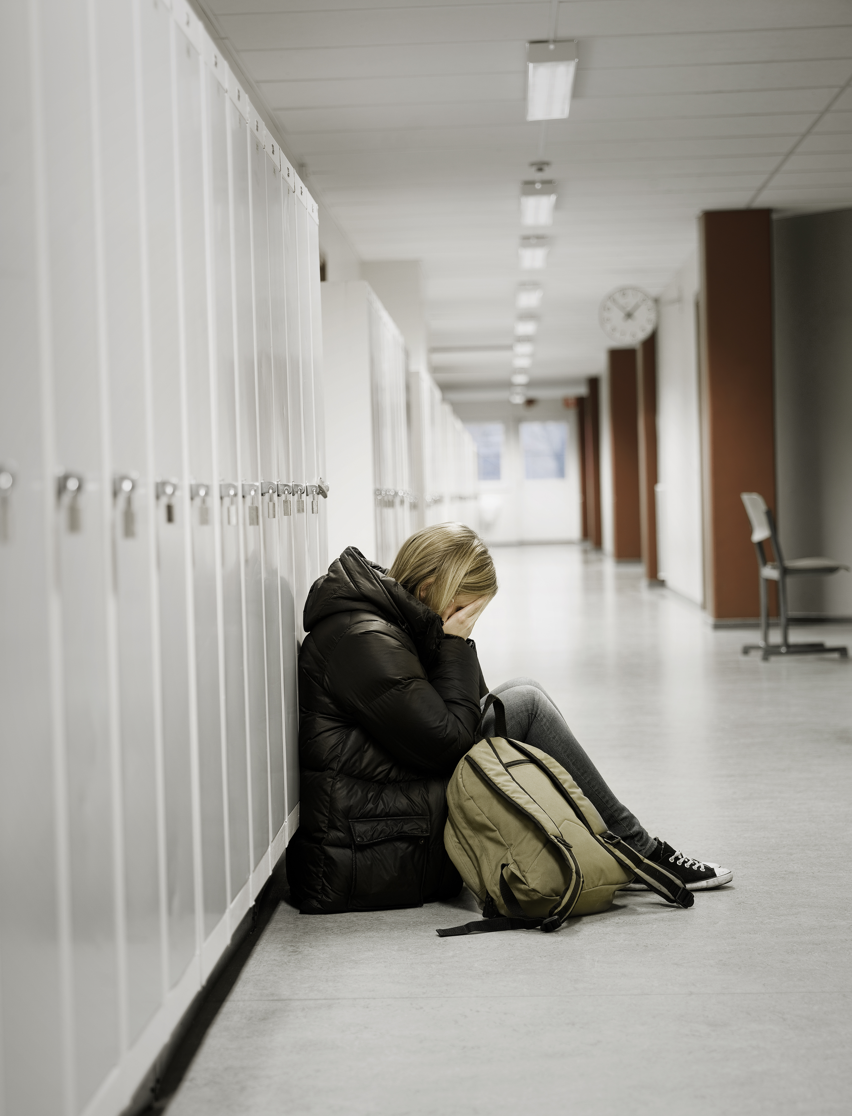 Young woman crying by the lockers at school. | Source: Shutterstock