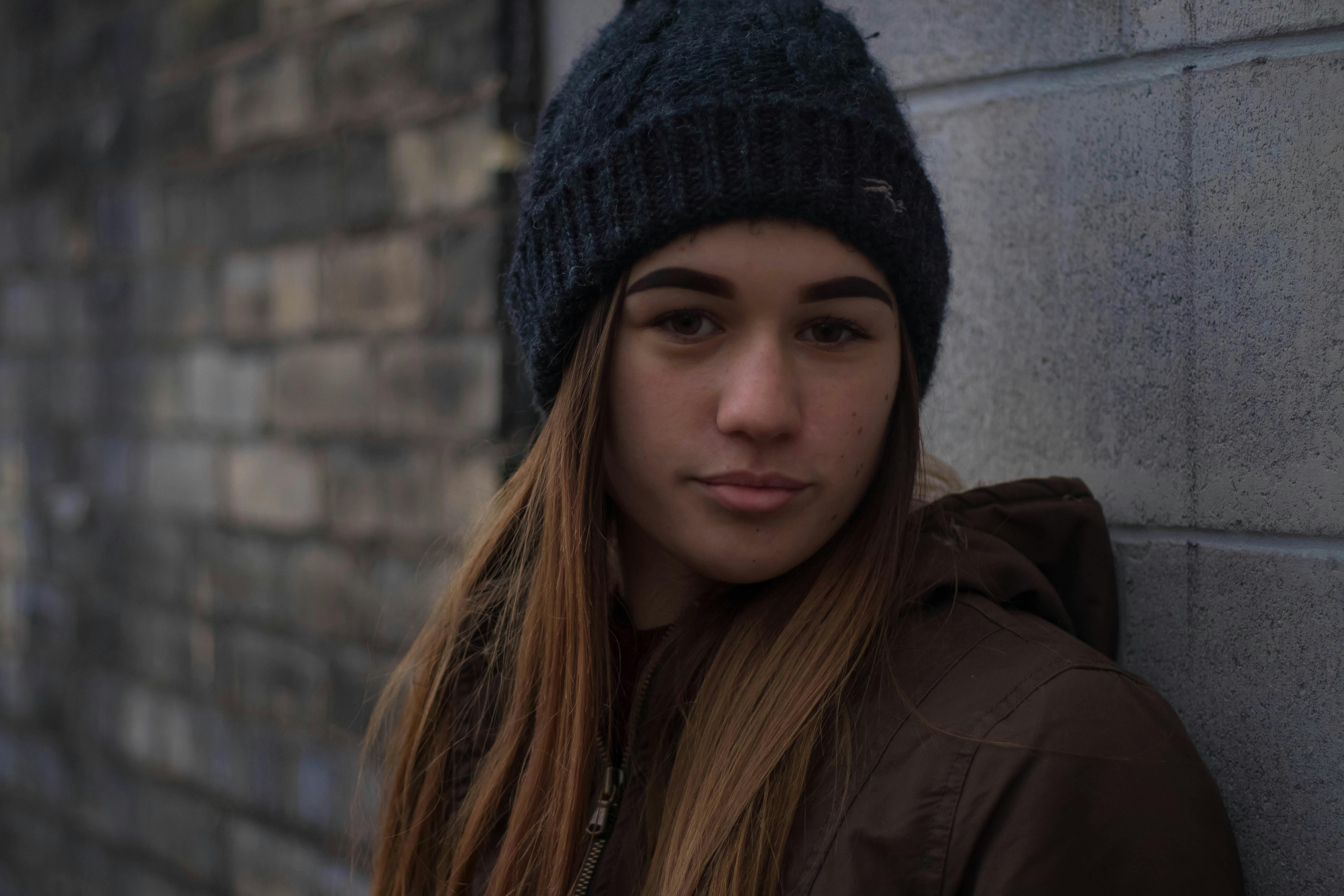 A neutral-looking teenage girl standing against a wall | Source: Pexels