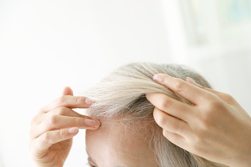 Une femme âgée en train de coiffer ses cheveux. | Photo : Getty Images