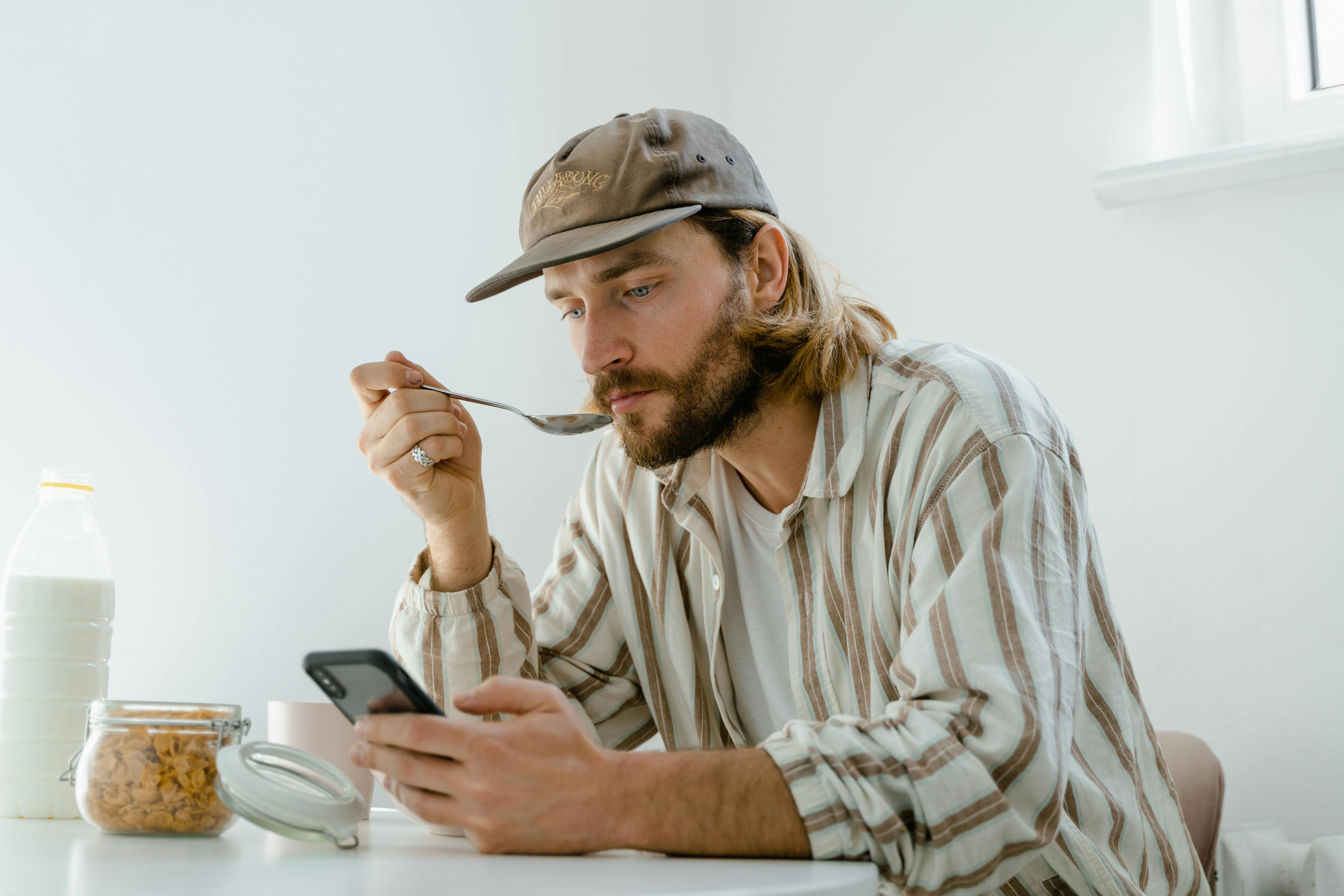 A man texting while eating breakfast | Source: Pexels