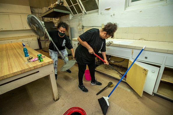 Des femmes néttoient des placars de cuisine. | Photo : Getty Images