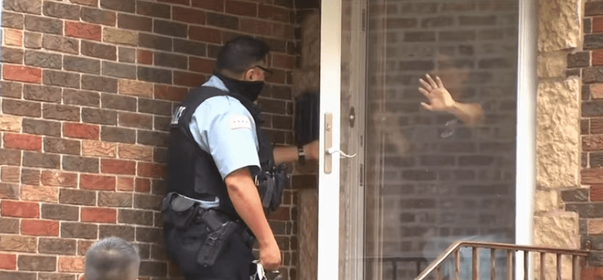 A screenshot of a policeman checking with witnesses who saw what happened to the baby who was abandoned in a Northwest Side alley in Chicago | Photo: Youtube/WGN News