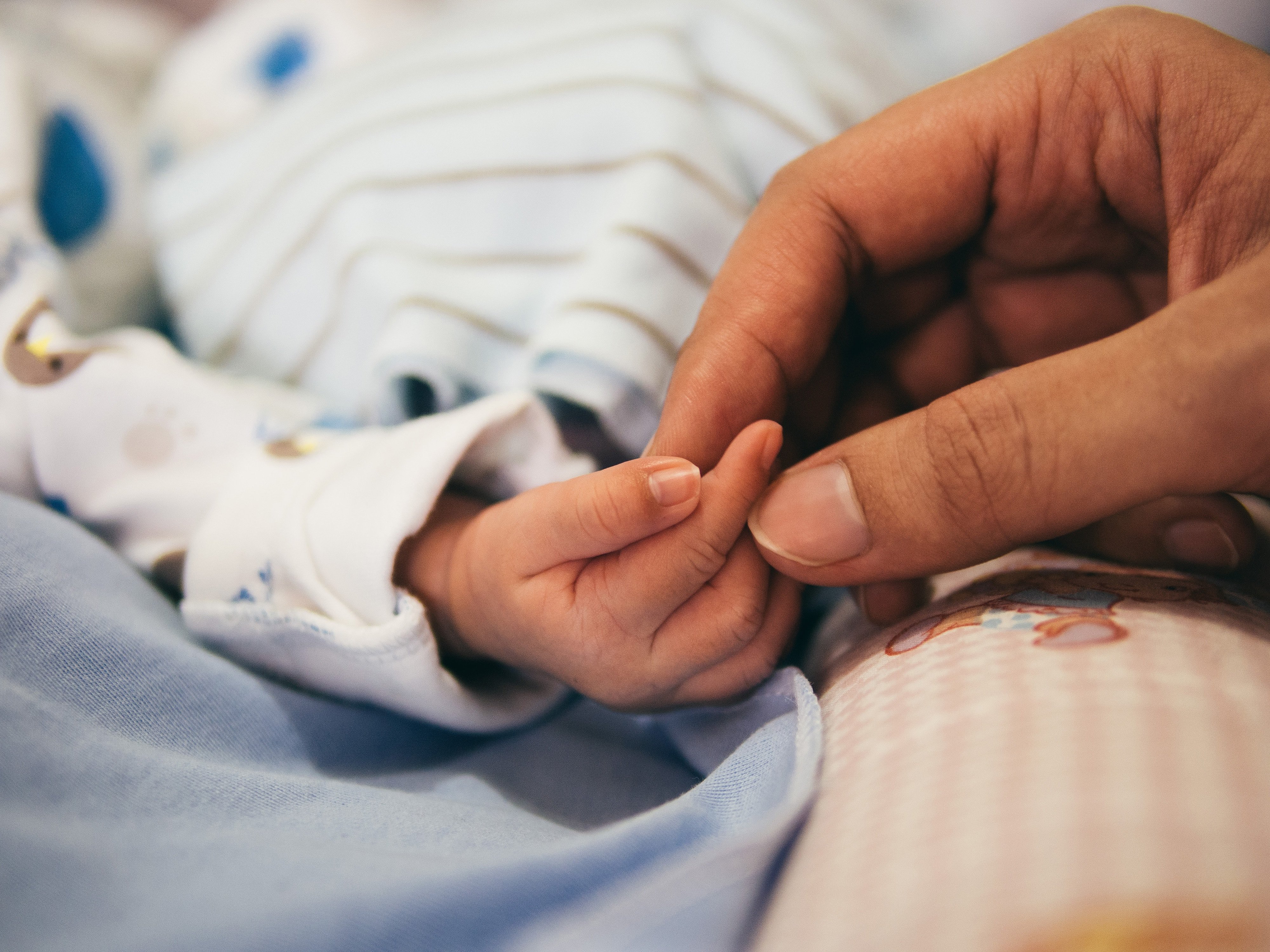 A lady holding a baby's hand in the hospital | Photo by Aditya Romansa on Unsplash