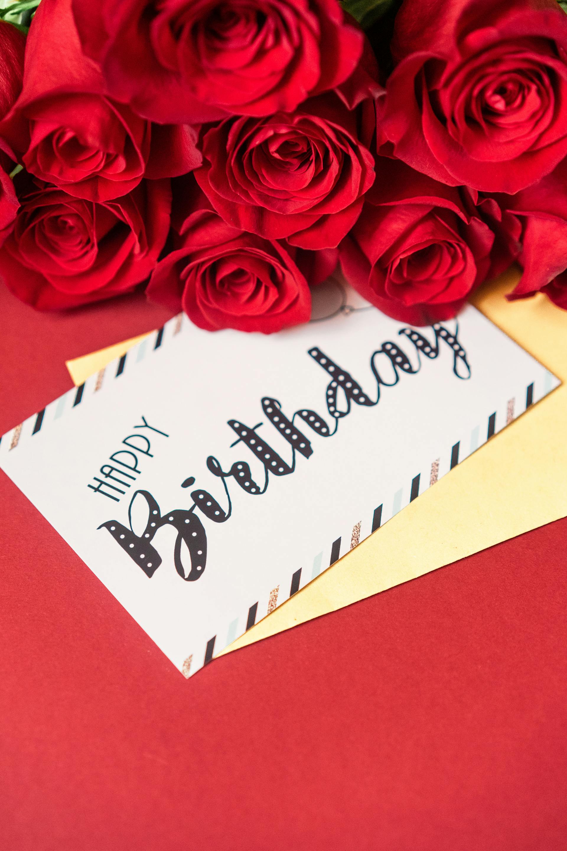 A postcard and a bouquet of red roses on a table | Source: Pexels