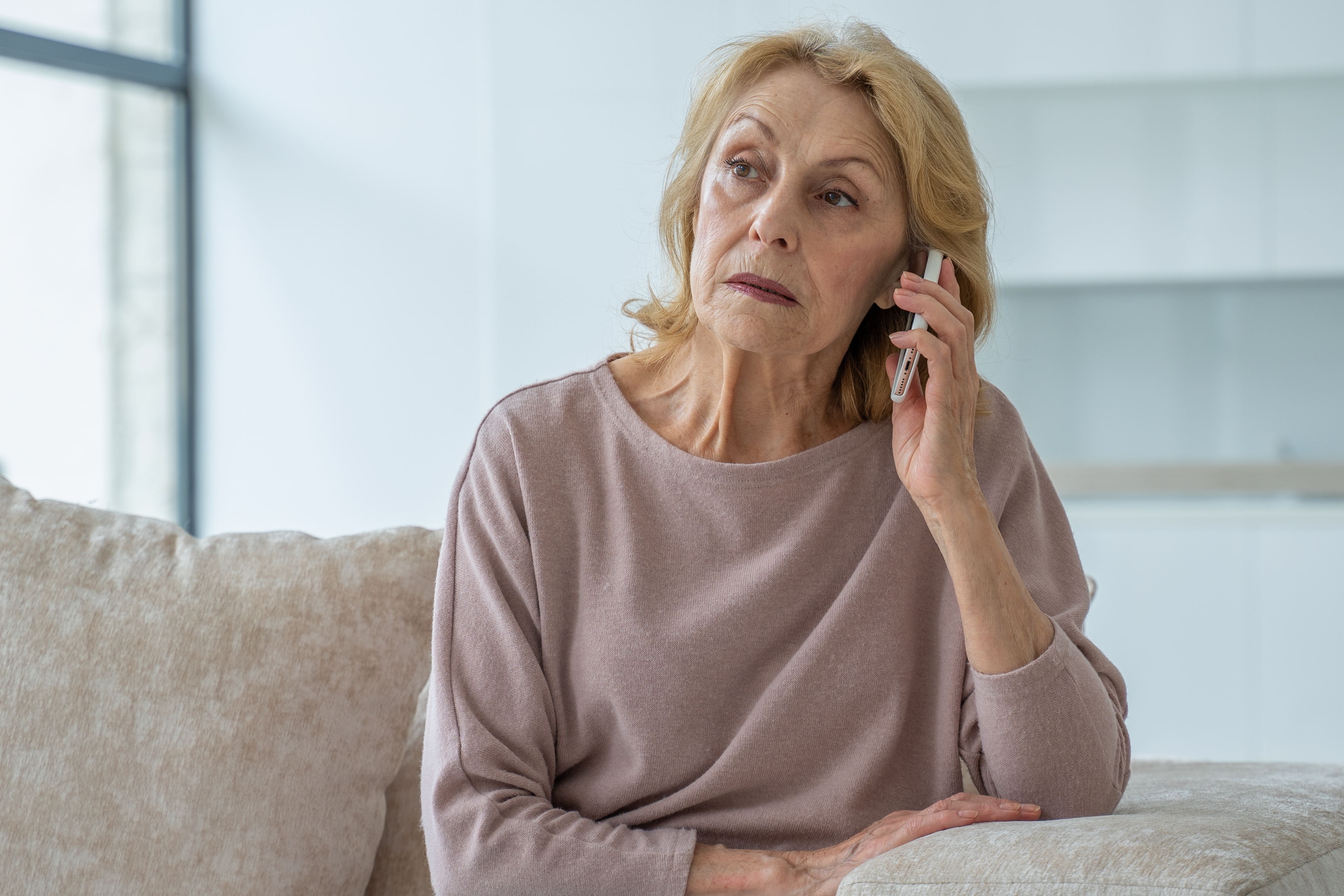 An elderly woman looking sad while on the phone | Source: Shutterstock