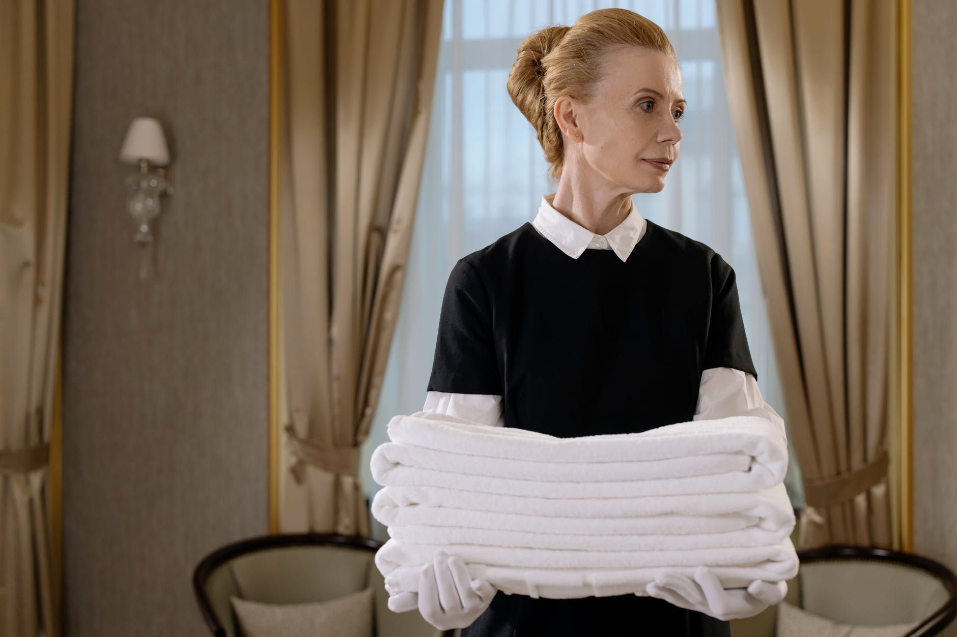 A housemaid carrying a pile of folded towels | Source: Pexels