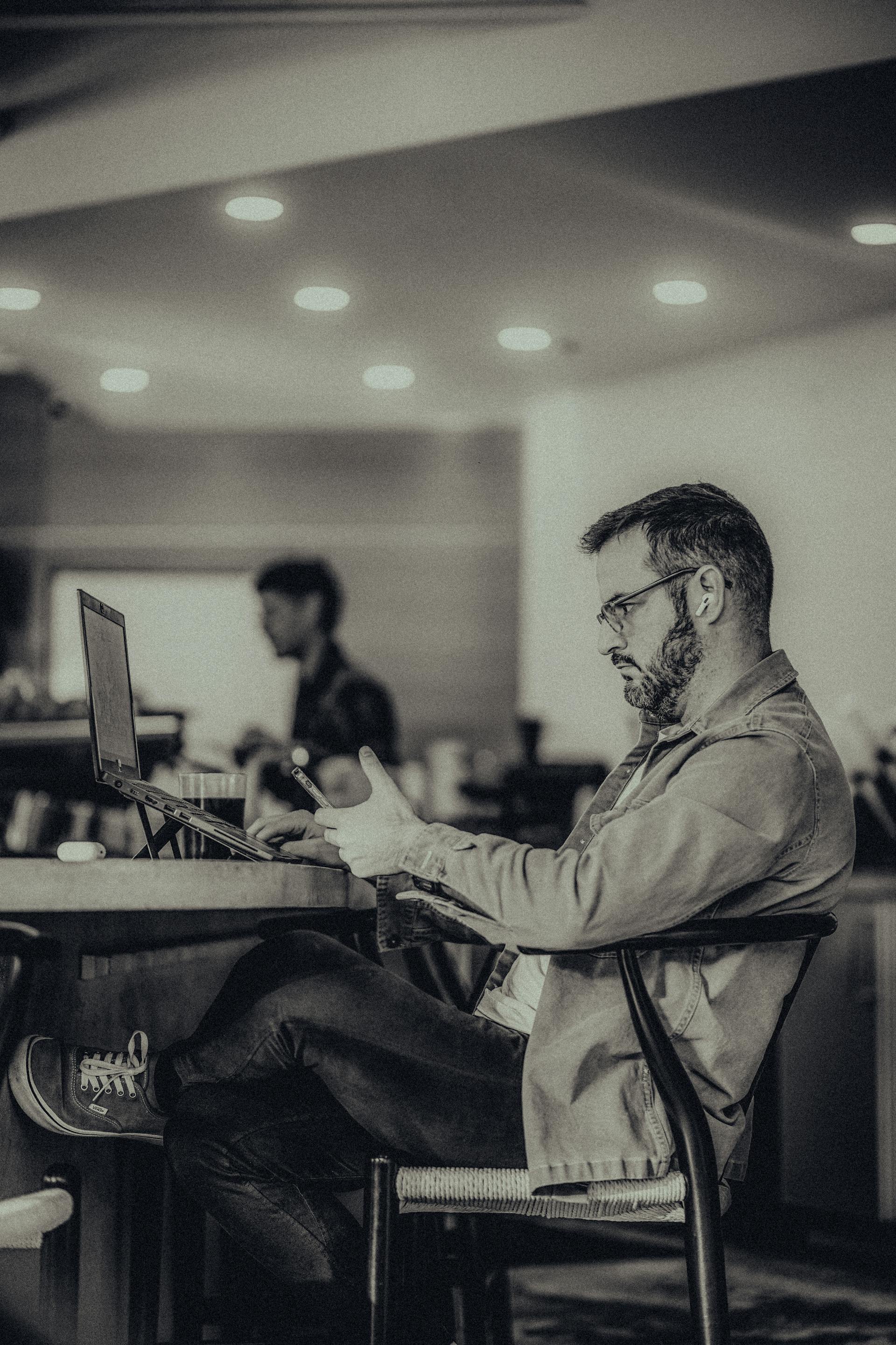 A man sitting in an office and using his phone | Source: Pexels