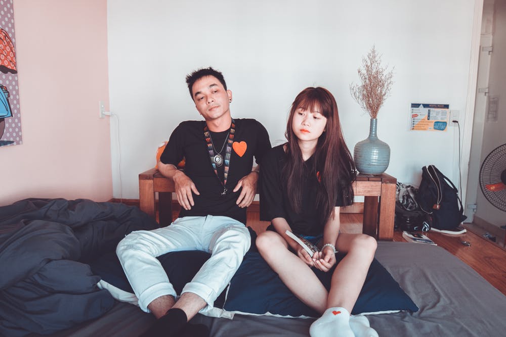 Un couple assis côte à côte sur le lit. | Photo: Pexels